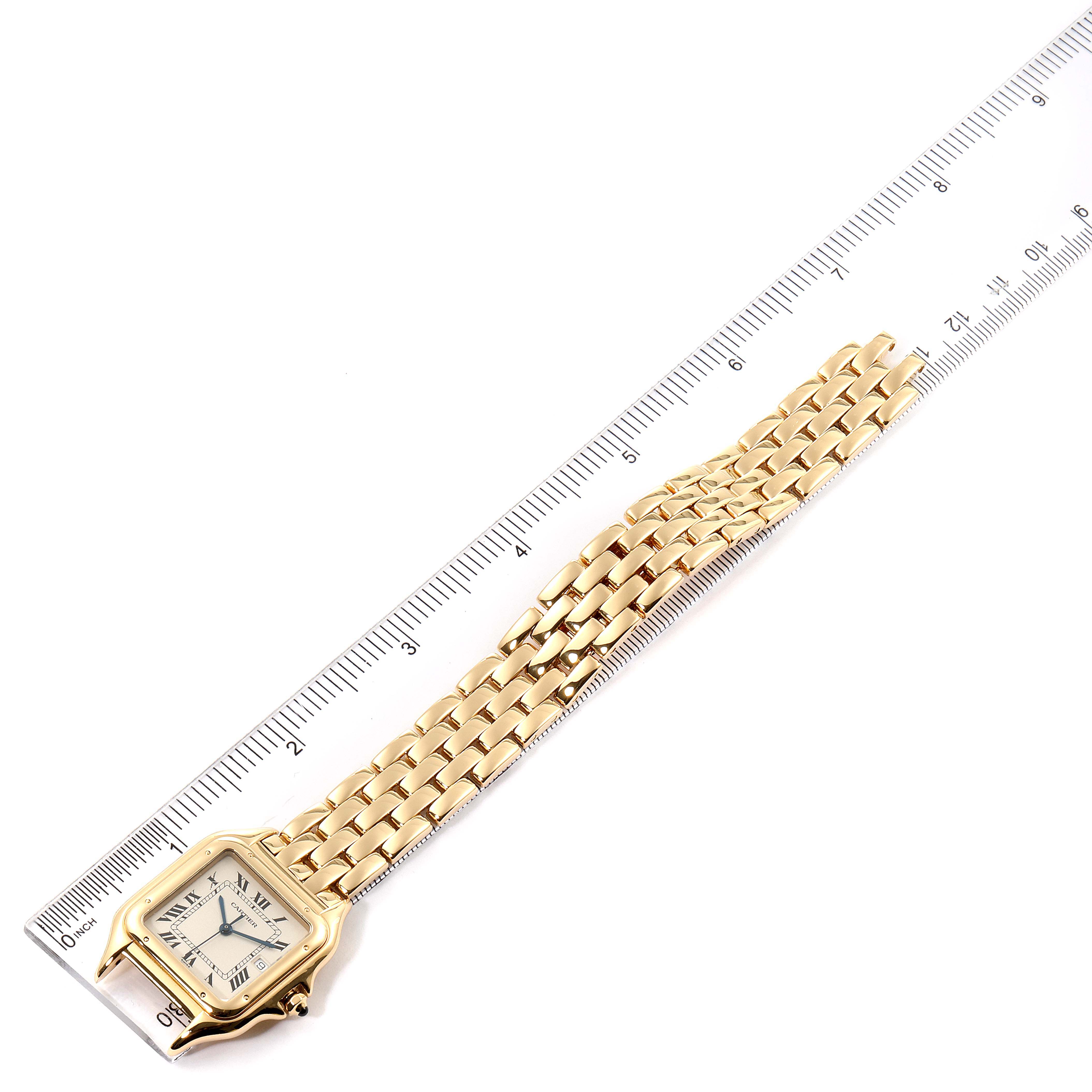 The image shows a top-down view of a Cartier Panthere W25014B9 Women's Yellow Gold Silver Dial W25014B9 Women's Yellow Gold Silver Dial watch next to a ruler, highlighting its face and part of its gold bracelet.