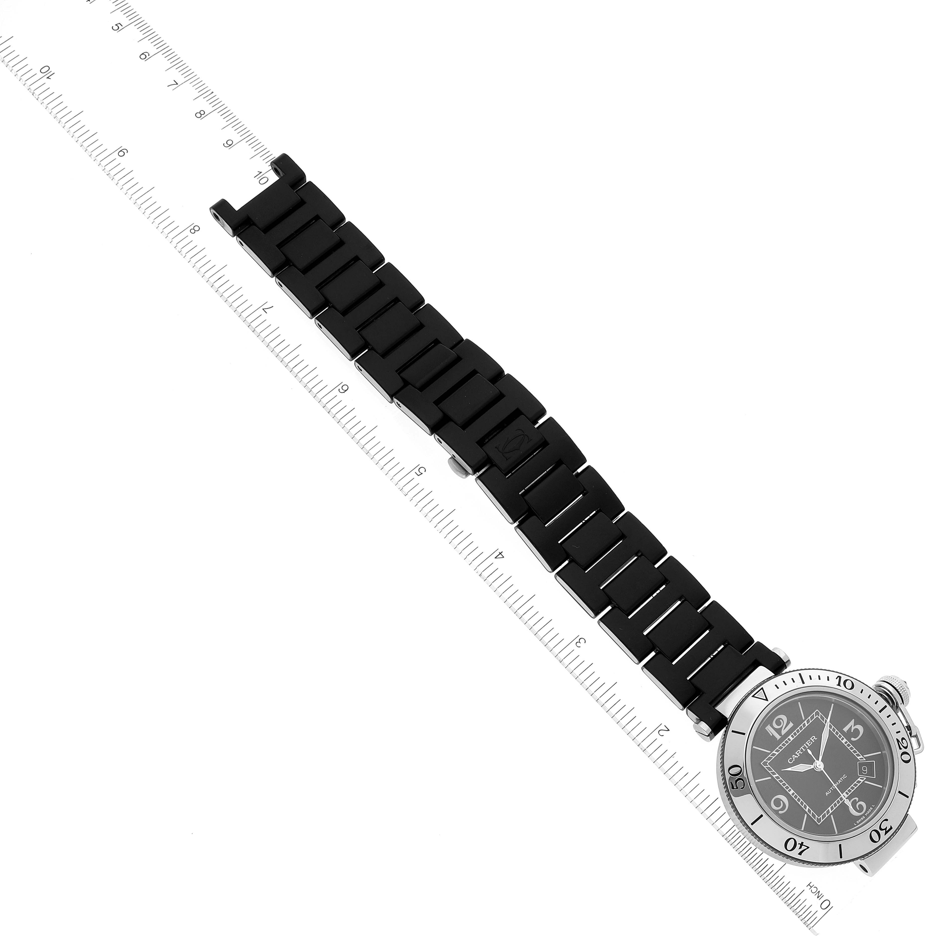 The Cartier Pasha W31077U2 Men's Stainless Steel Black Dial W31077U2 Men's Stainless Steel Black Dial watch is shown from a top-down angle, displaying its face and black link bracelet next to a ruler.