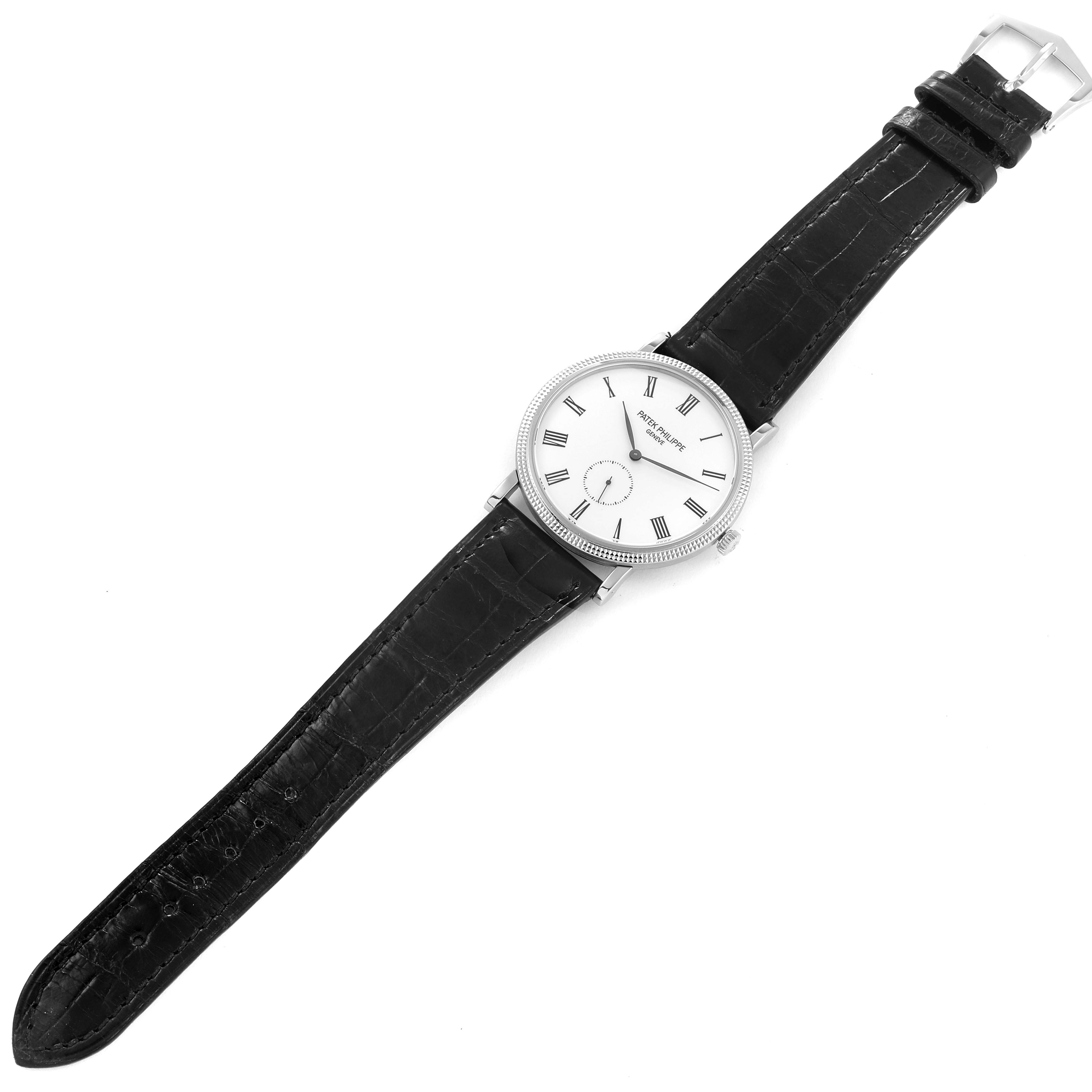 The image shows a Patek Philippe Calatrava 5119G Men's White Gold White Dial 5119G Men's White Gold White Dial watch with a white dial, black leather strap, and a silver buckle, viewed from the top.