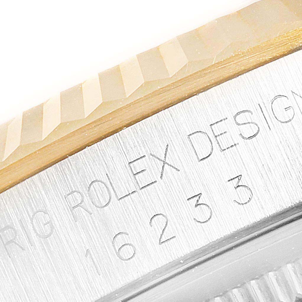 This close-up image of a Rolex Datejust 16233 Men's Steel and Gold (two tone) Champagne Dial 16233 Men's Steel and Gold (two tone) Champagne Dial watch shows the engraved serial number and part of the fluted bezel.