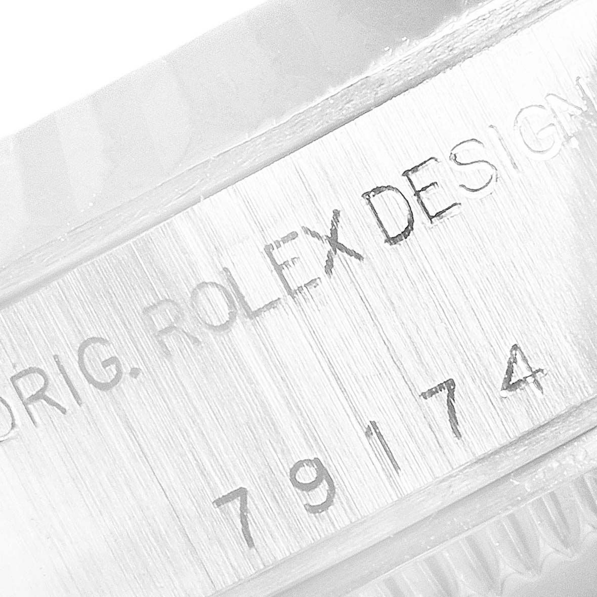 This close-up image shows the engraved model number and "ORIG. ROLEX DESIGN" text on the case of a Rolex Datejust 79174 Women's Stainless Steel Silver Dial 79174 Women's Stainless Steel Silver Dial watch.