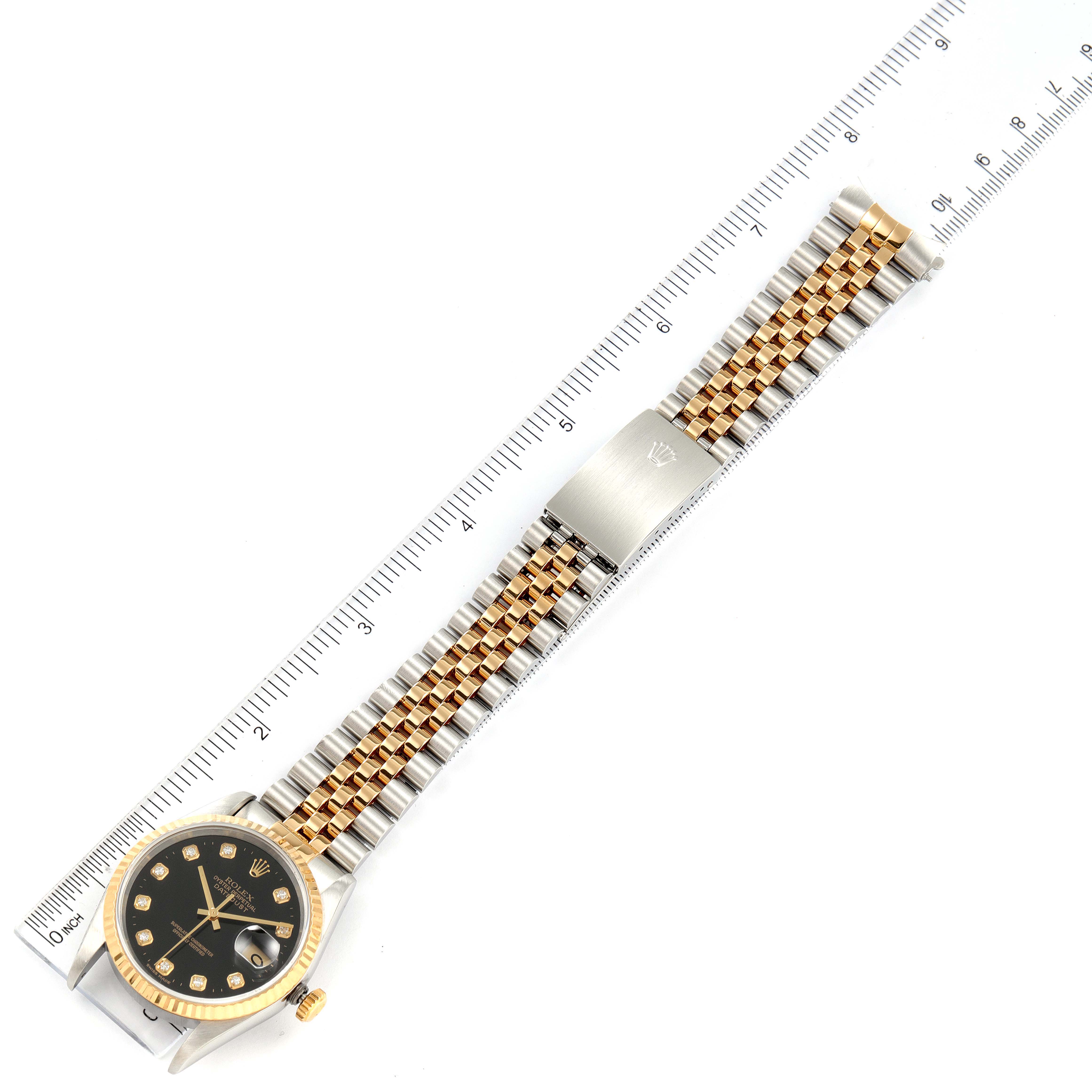 The image shows a Rolex Datejust 16233 Men's Steel and Gold (two tone) Black Dial 16233 Men's Steel and Gold (two tone) Black Dial watch laid flat, showcasing the black dial, gold fluted bezel, and jubilee bracelet with a ruler for scale.