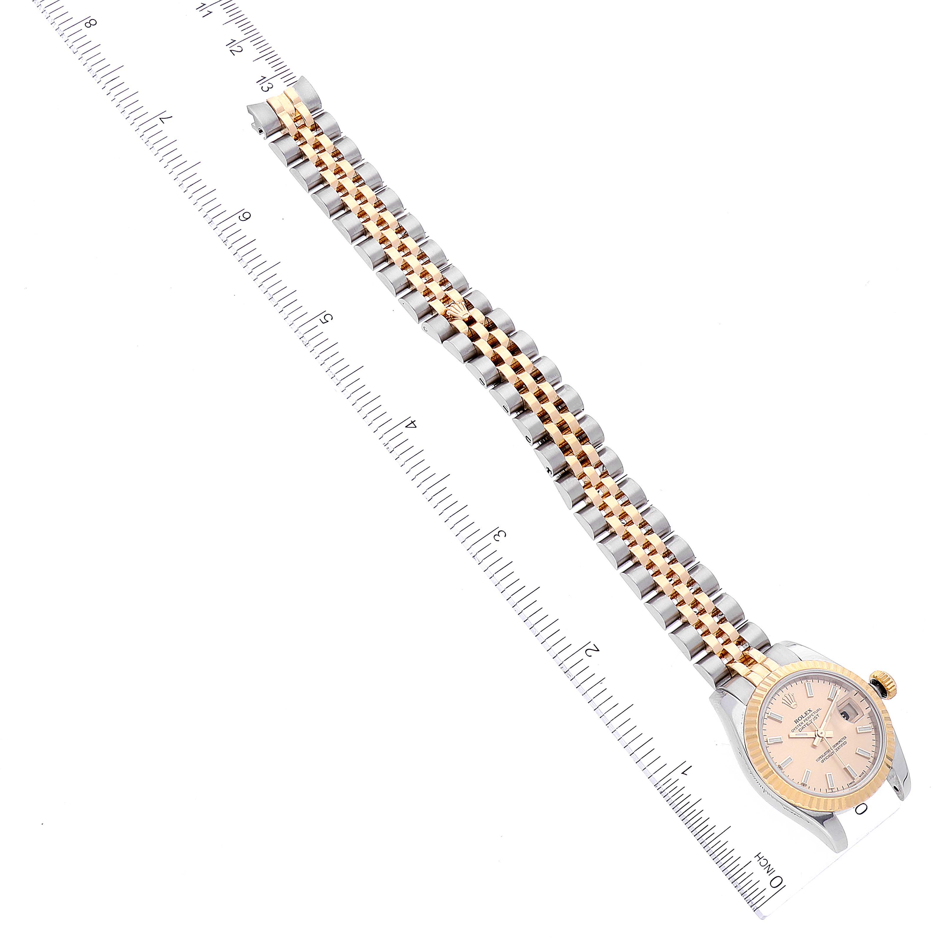The Rolex Datejust 179173 Women's Steel and Gold (two tone) Champagne Dial 179173 Women's Steel and Gold (two tone) Champagne Dial is shown from a top-down angle with the entire band and watch face visible, placed alongside a ruler.