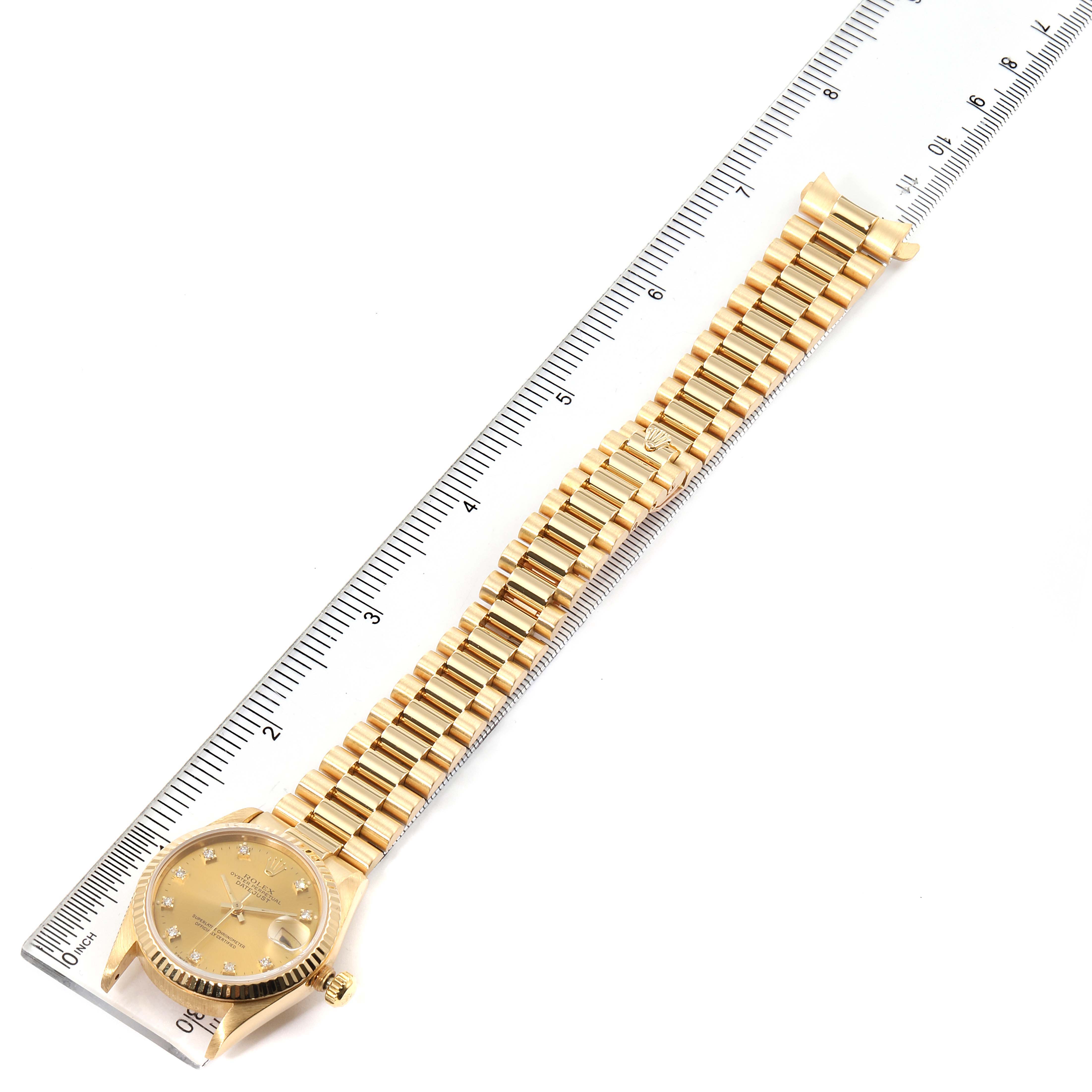 The image shows a gold Rolex President 68278 Women
s Yellow Gold Champagne Dial 68278 Women
s Yellow Gold Champagne Dial model watch with a view of the entire watch, including its face and bracelet, against a ruler for scale.
