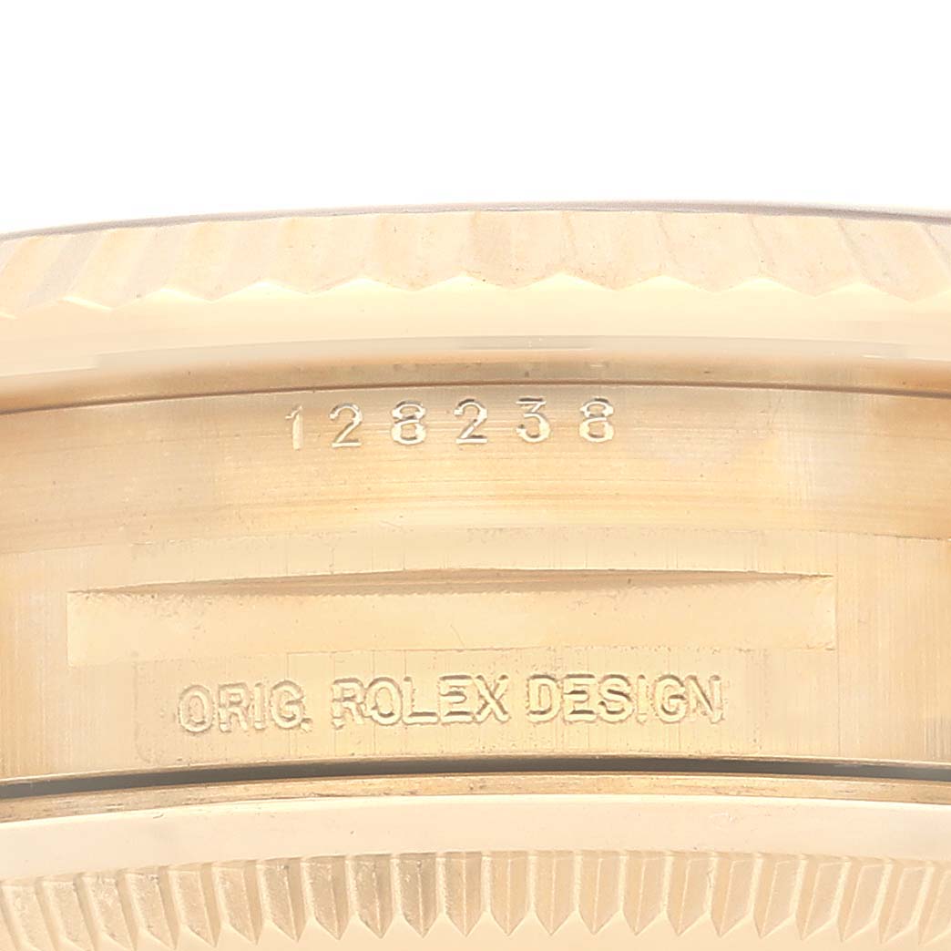 The image shows a close-up view of the interior of the case back of a Rolex President 128238 Men
s Yellow Gold White Dial 128238 Men
s Yellow Gold White Dial model watch with engravings of its design and model number.