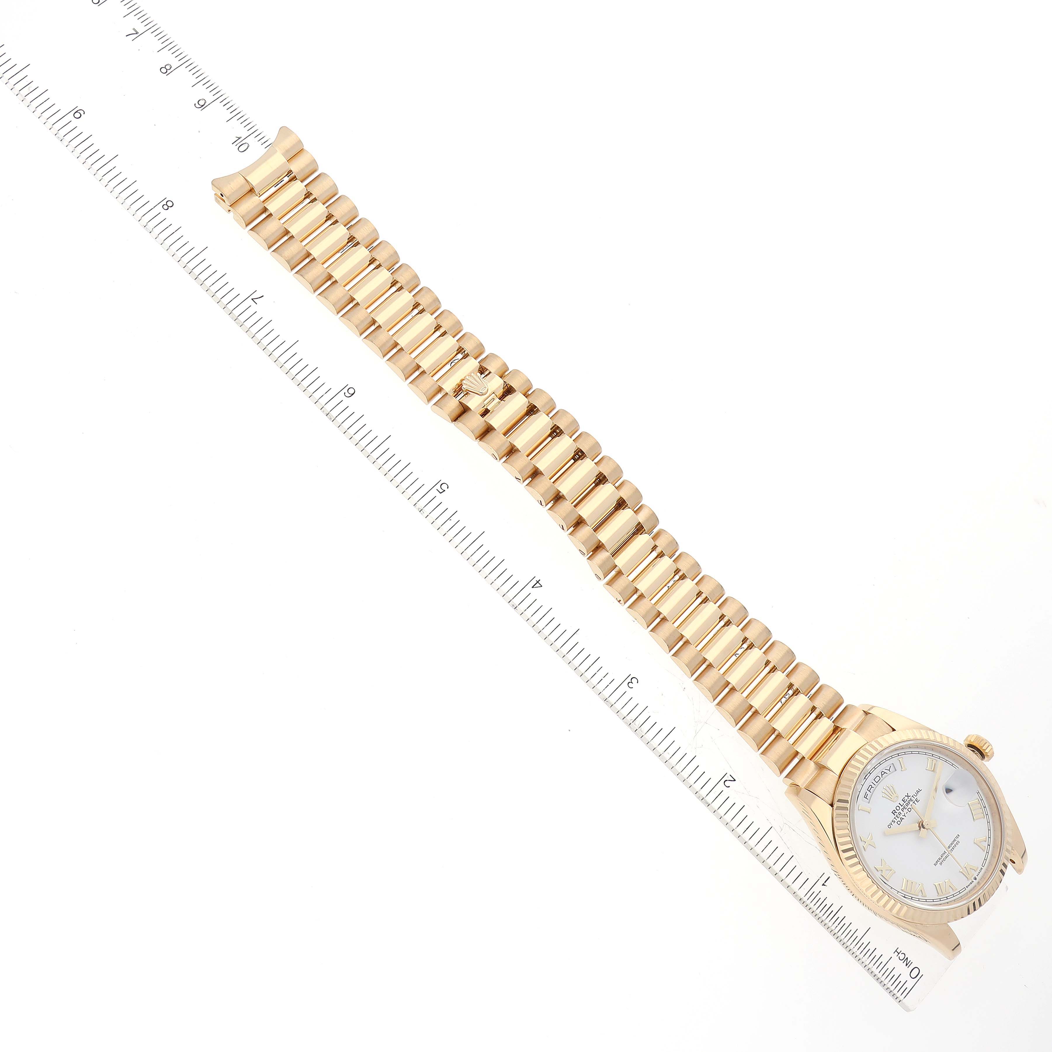 The image shows a Rolex President 128238 Men
s Yellow Gold White Dial 128238 Men
s Yellow Gold White Dial model watch lying flat, with the face and bracelet band visible alongside a ruler for scale.