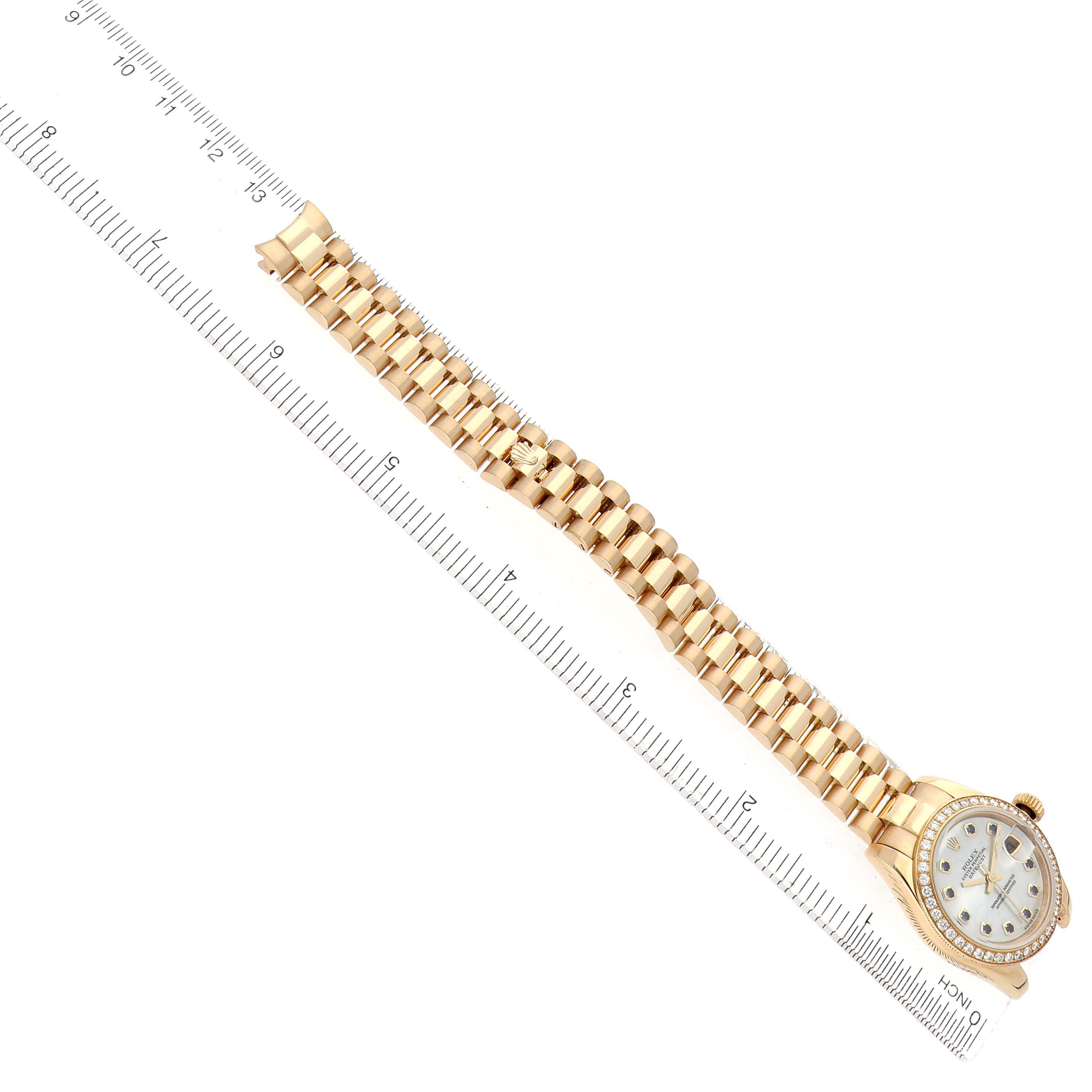 The Rolex President 179138 Women's Yellow Gold Mother of Pearl Dial model watch is shown from a top angle, featuring its full bracelet, face, and bezel alongside a ruler for scale.