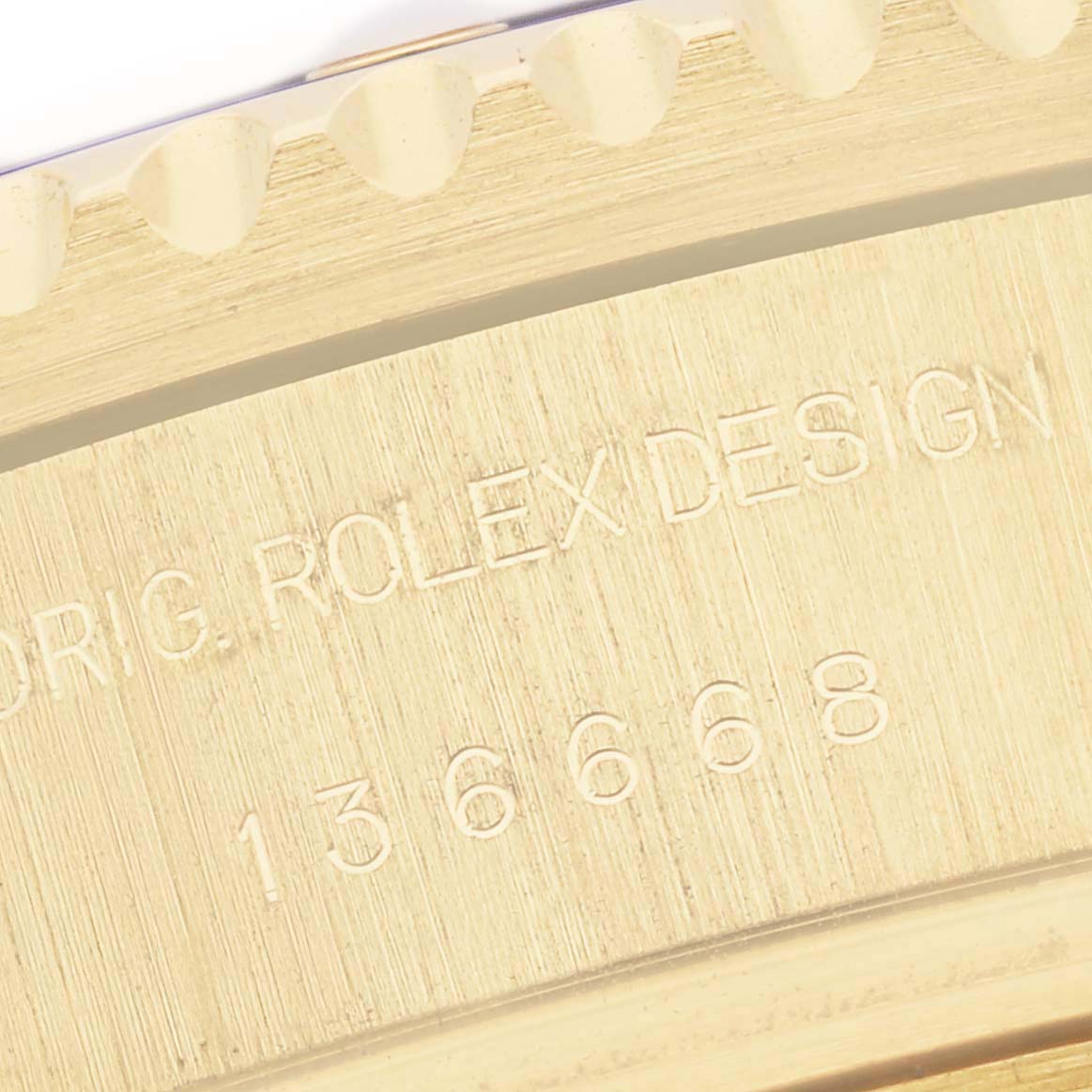 The image shows a close-up of the side detailing on a Rolex Sea-Dweller 136668 Men's Yellow Gold Blue Dial, highlighting the engraved design and model number.