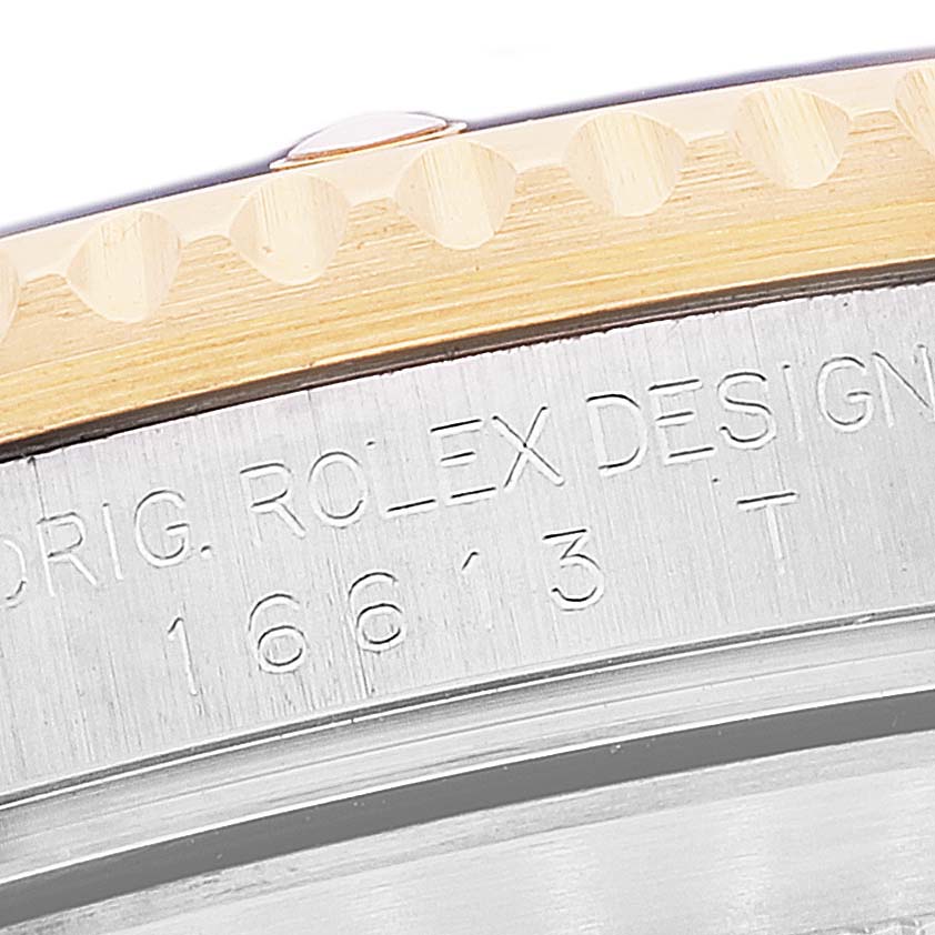 The image shows a close-up angle of the Rolex Submariner 16613 Men's Steel and Gold (two tone) Blue Dial 16613 Men's Steel and Gold (two tone) Blue Dial's bezel and engraved case side.