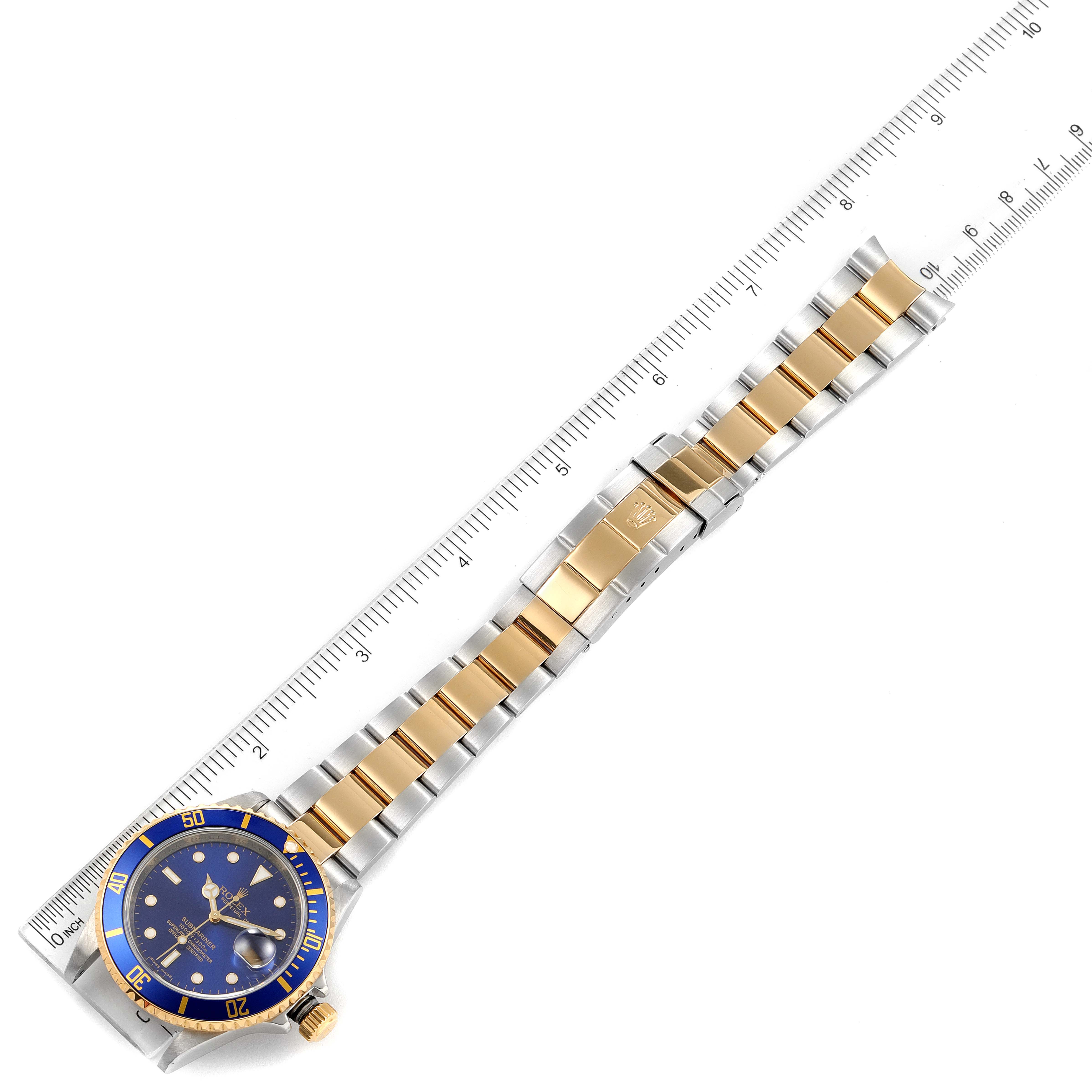 The image shows a top view of a Rolex Submariner 16613 Men
s Steel and Gold (two tone) Blue Dial 16613 Men
s Steel and Gold (two tone) Blue Dial watch with its full bracelet next to a ruler for measurement.