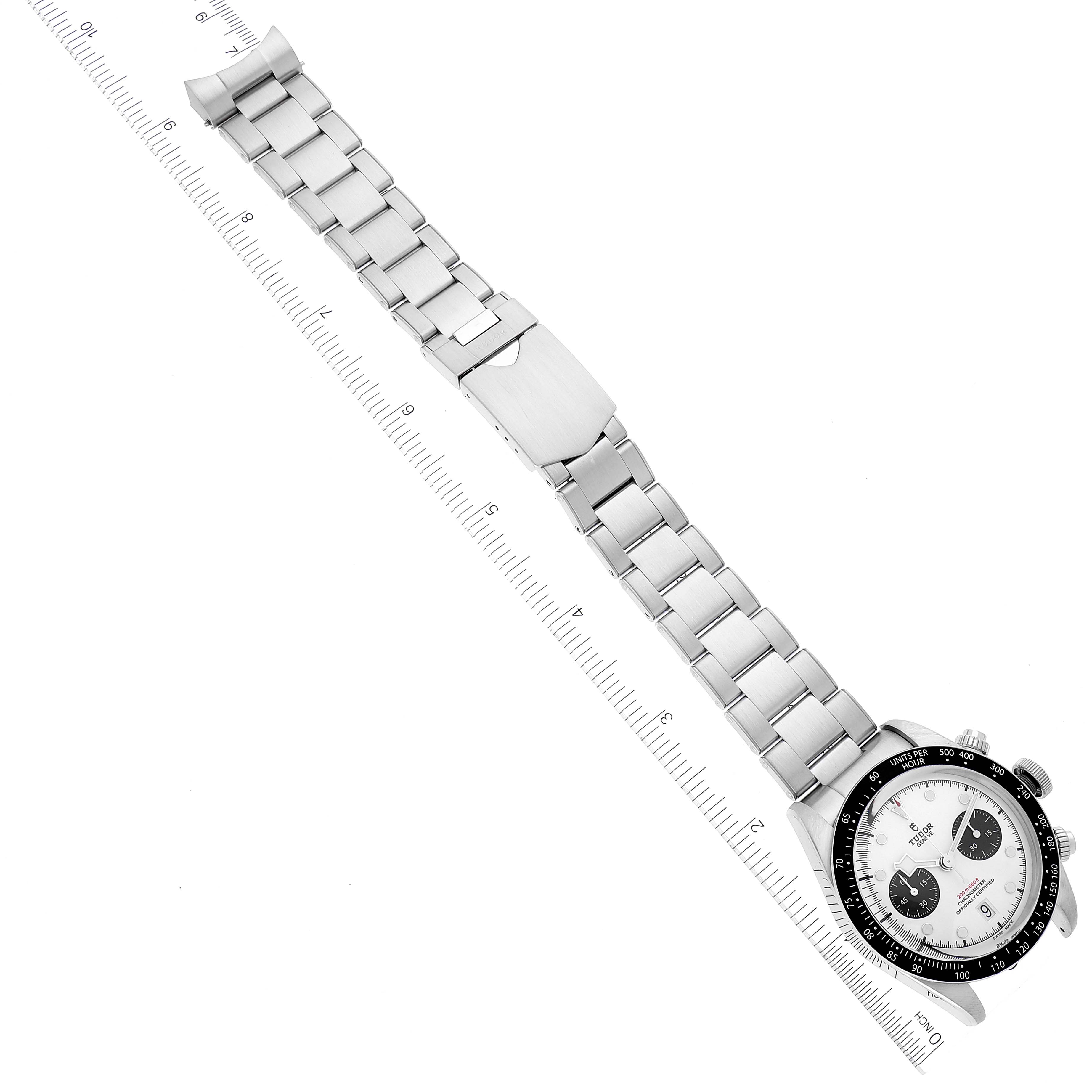 The image shows a Tudor Heritage Black Bay 79360N Men
s Stainless Steel White Dial 79360N Men
s Stainless Steel White Dial watch with a full view of its metal bracelet and clasp, positioned along a ruler.