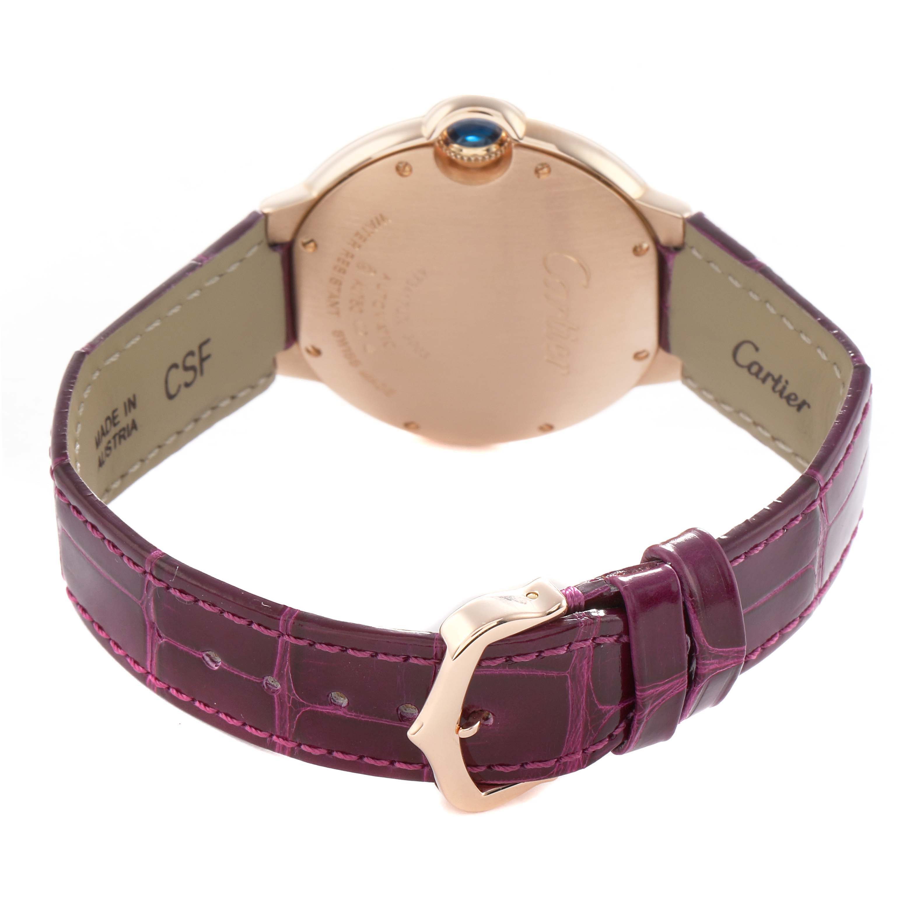 The image shows the back of a Cartier Ballon Bleu WE902028 Women's Rose Gold Silver Dial watch with a purple strap and rose gold buckle, highlighting the crown and case back.