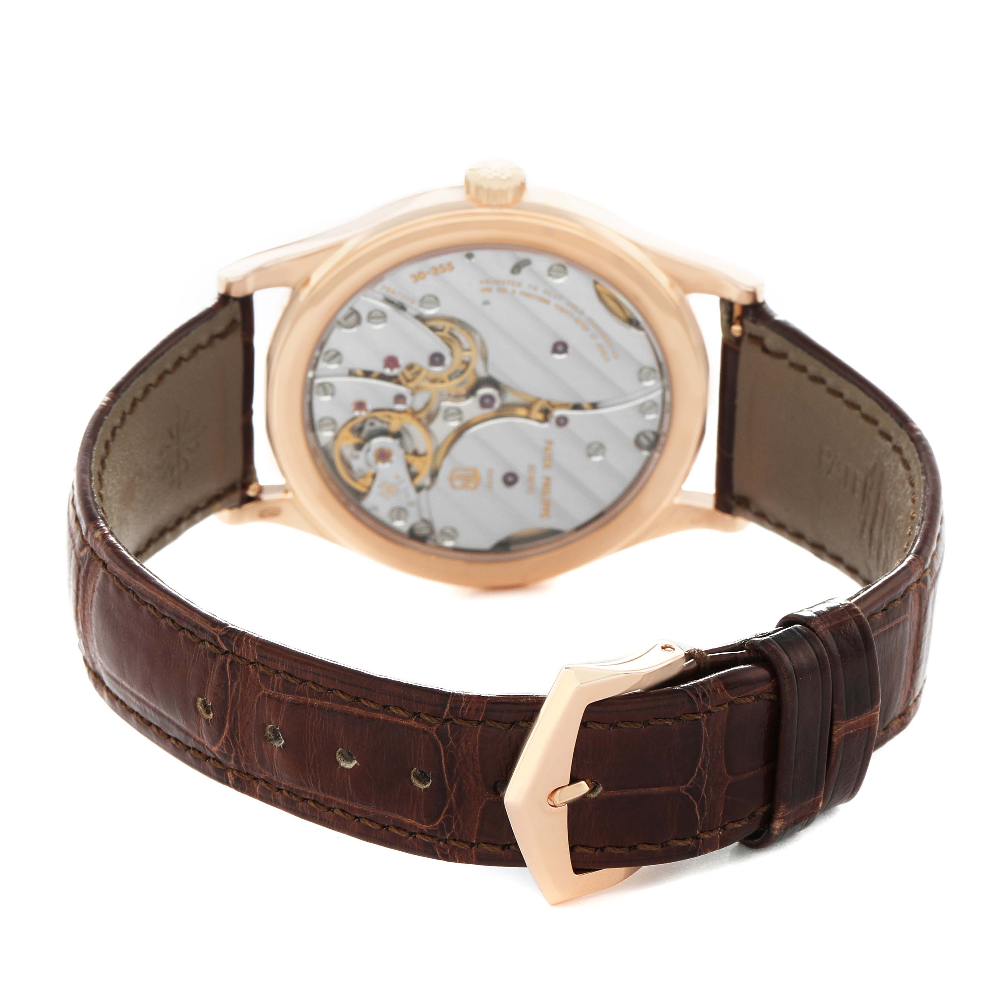 The Patek Philippe Calatrava 6119R-001 Men's Rose Gold Silver Dial watch is shown from a rear angle, highlighting the movement and brown leather strap.