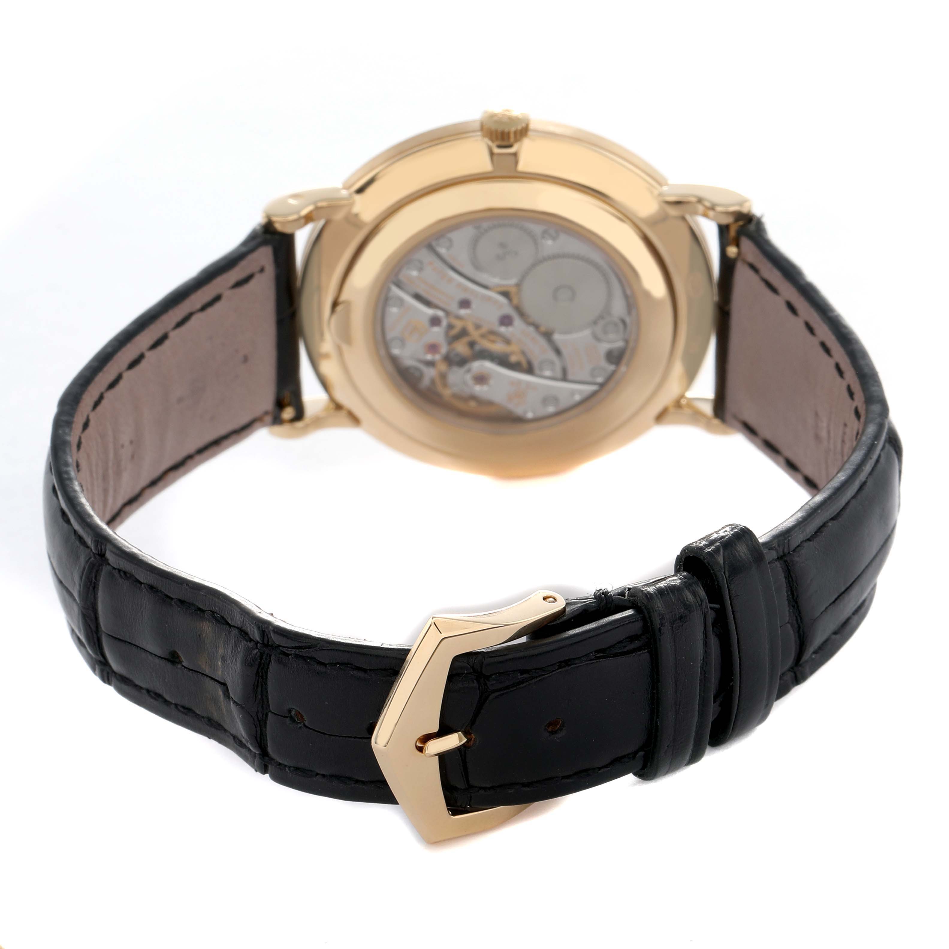 The image shows the back view of a Patek Philippe Calatrava 5119J Men's Yellow Gold White Dial, highlighting the open case back and leather strap.