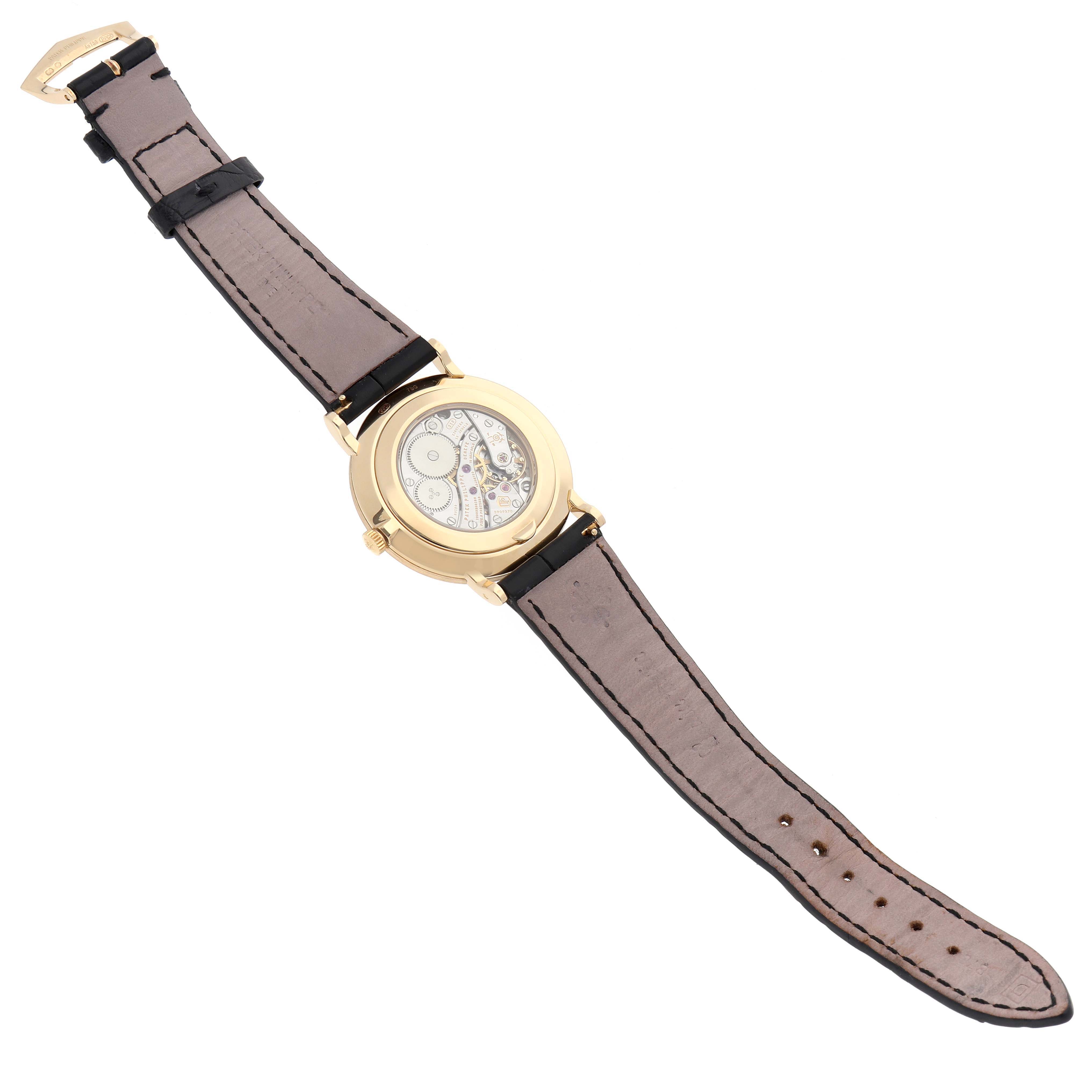 The Patek Philippe Calatrava 5119J Men's Yellow Gold White Dial watch is shown from the back, highlighting the case back and leather strap.