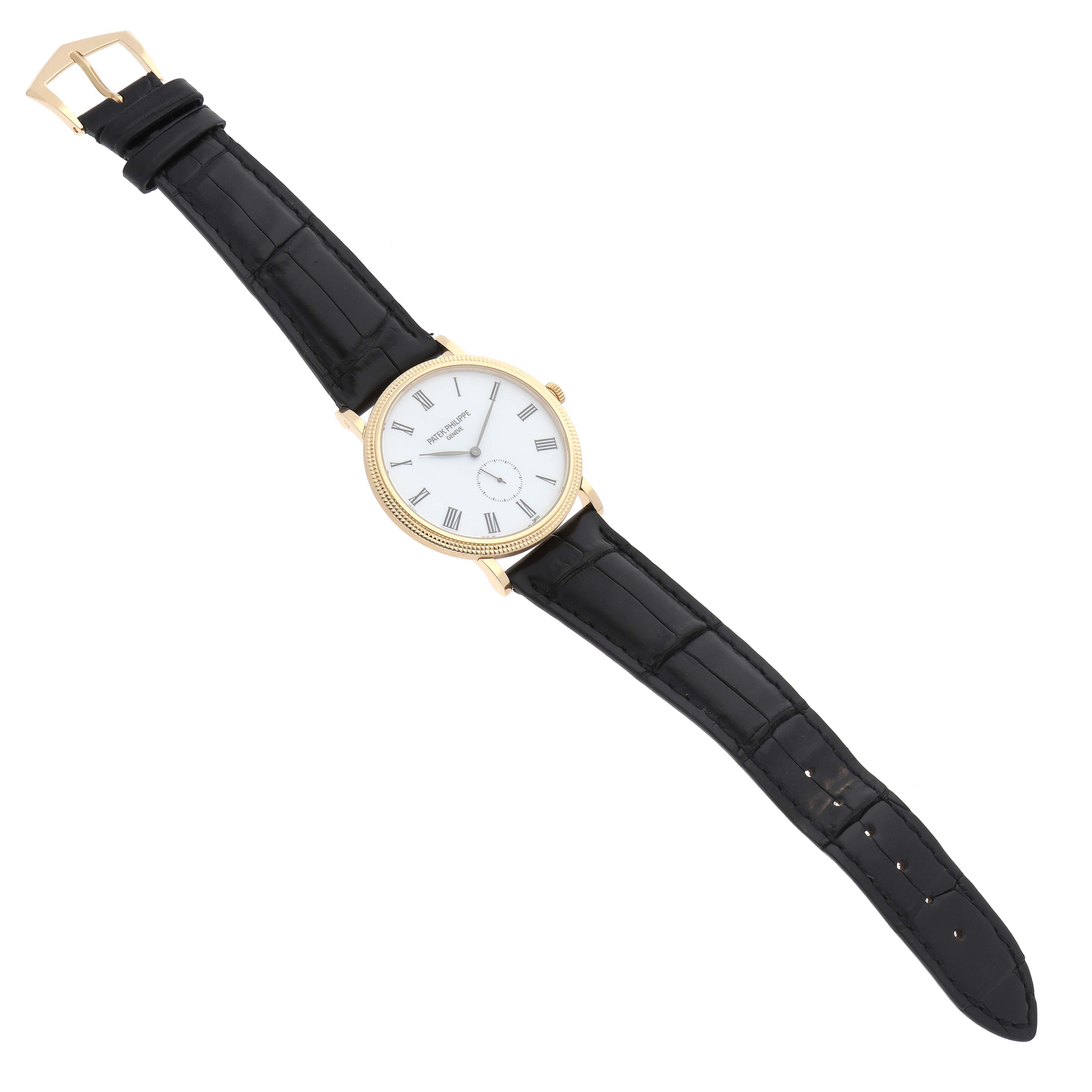This image shows a Patek Philippe Calatrava 5119J Men's Yellow Gold White Dial watch laid flat, displaying the full face, case, and black leather strap from a top-down angle.