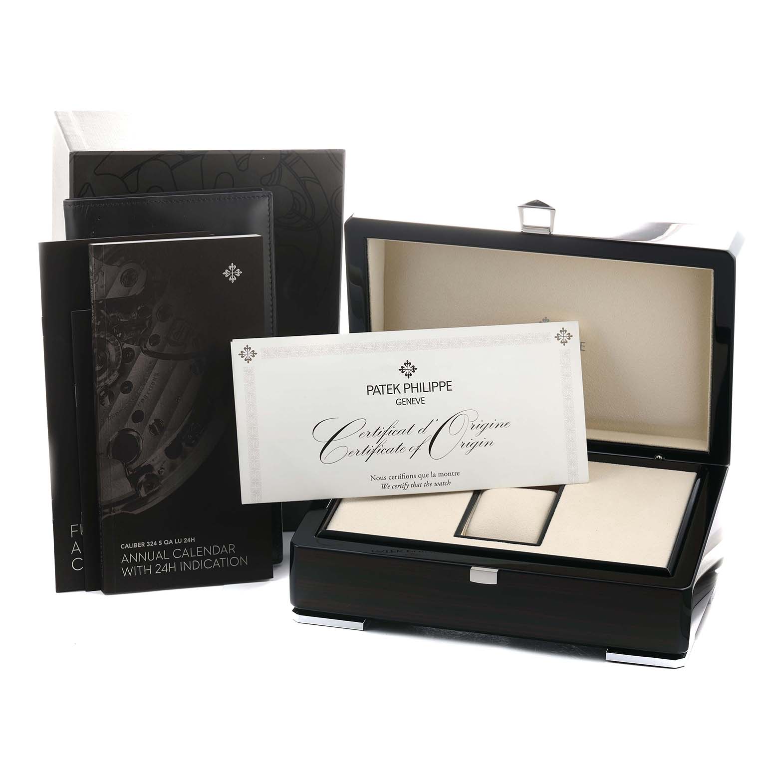 The image shows a Patek Philippe Complications 5205G-013 Men's White Gold Blue Dial watch box at an angle, with documents and a certificate of origin displayed.