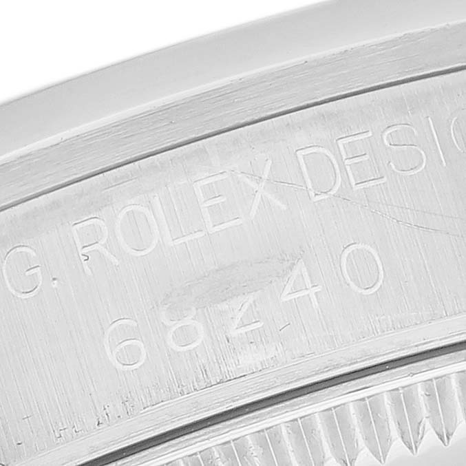 The image shows an angled close-up of the engraved inner bezel and serrated edge of a Mid-Size Rolex watch.
