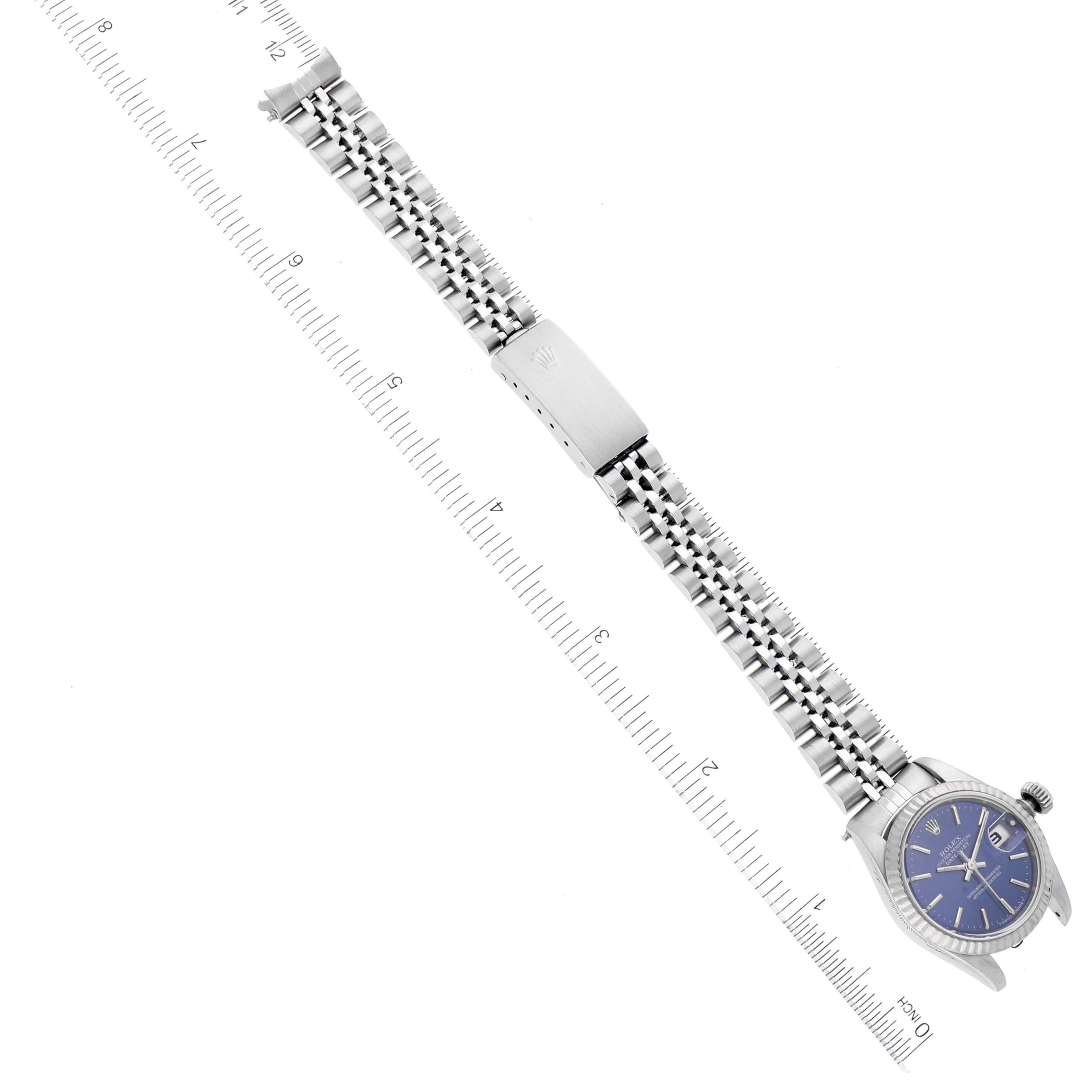The image shows a Rolex Datejust 69174 Women's Stainless Steel Blue Dial 69174 Women's Stainless Steel Blue Dial watch laid flat, highlighting the face, bezel, and bracelet, alongside a measuring ruler for scale.