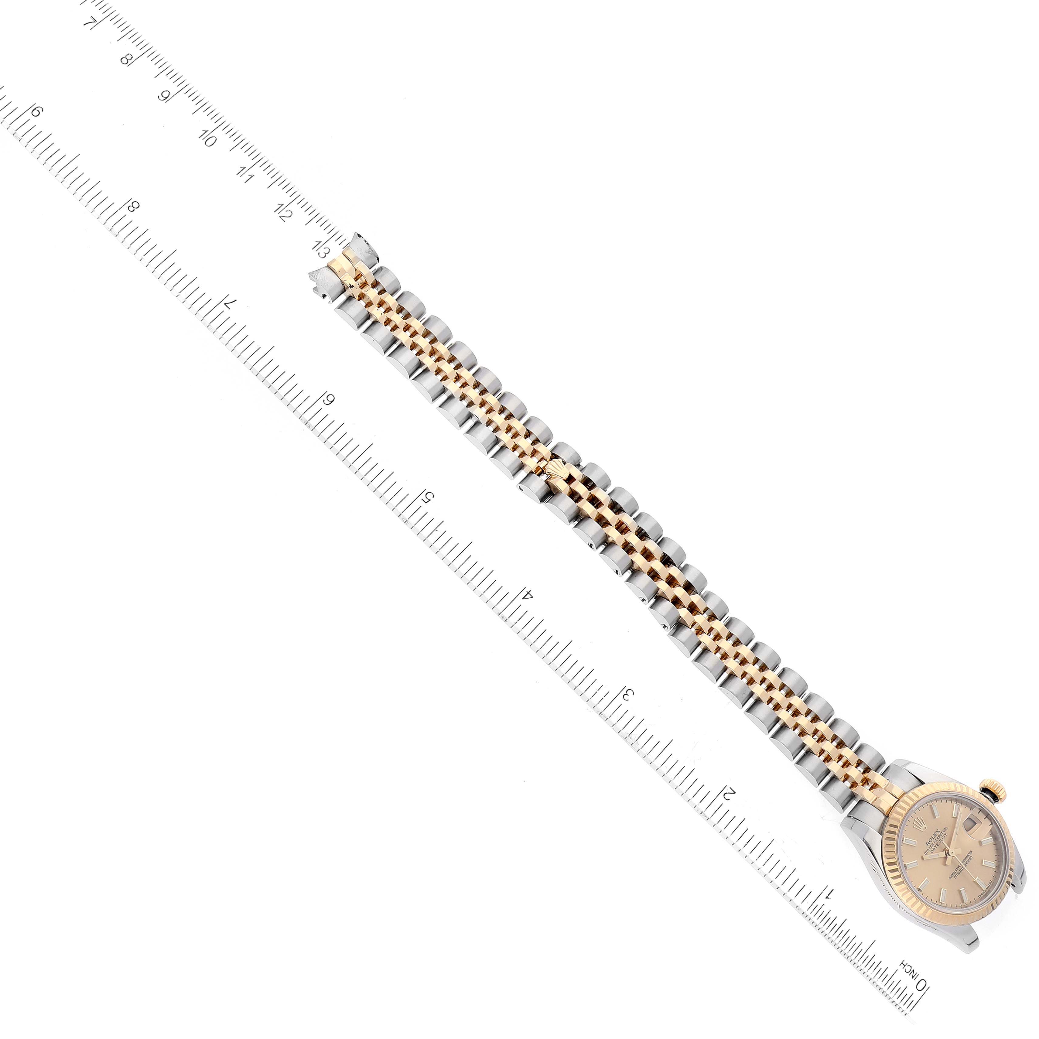This image shows a Rolex Datejust 179173 Women's Steel and Gold (two tone) Champagne Dial 179173 Women's Steel and Gold (two tone) Champagne Dial watch angled diagonally with the full bracelet and part of the watch face visible next to a ruler.