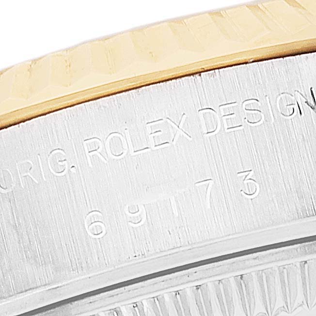 The image shows a close-up of the rim and case sides of a Rolex Datejust 69173 Women's Steel and Gold (two tone) Blue Dial 69173 Women's Steel and Gold (two tone) Blue Dial watch, featuring engraved text and the gold bezel.