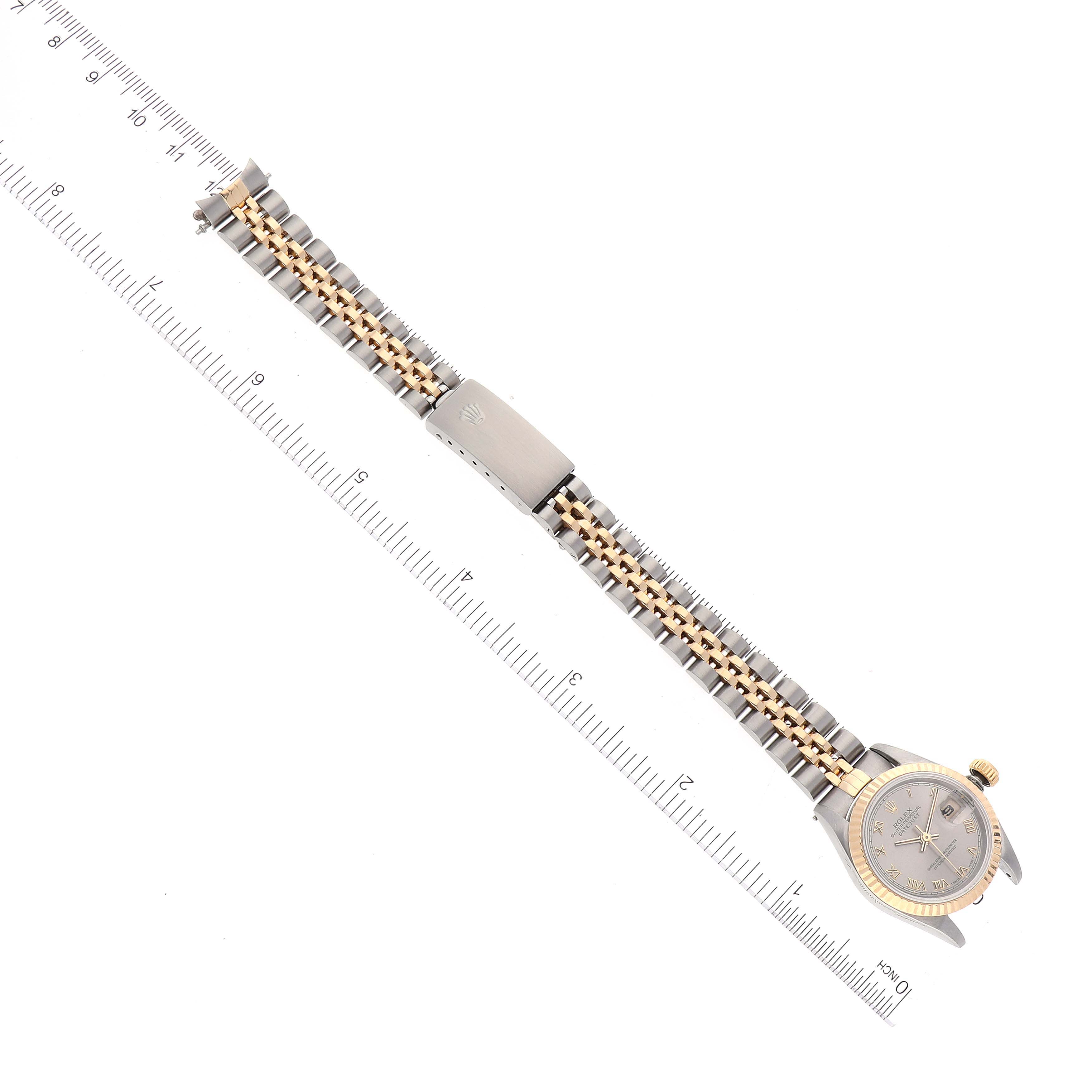 The Rolex Datejust 69173 Women
s Steel and Gold (two tone) Grey Dial 69173 Women
s Steel and Gold (two tone) Grey Dial watch is shown from an overhead view, displaying the dial, bracelet, and clasp against a ruler for scale.
