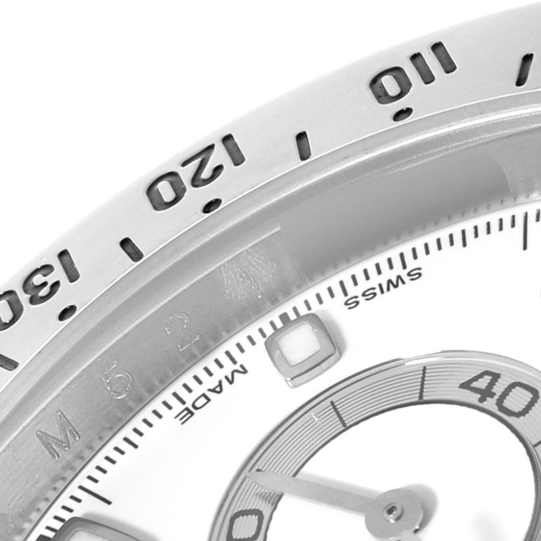 The image shows a close-up of the Rolex Daytona 116520 Men's Stainless Steel White Dial 116520 Men's Stainless Steel White Dial's bezel and part of its dial at an oblique angle.