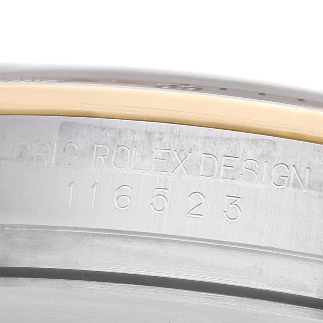 The image shows a close-up of the side of a Rolex Daytona 116523 Men's Steel and Gold (two tone) Silver Dial watch, highlighting the engraved model number "116523" on the metal case.