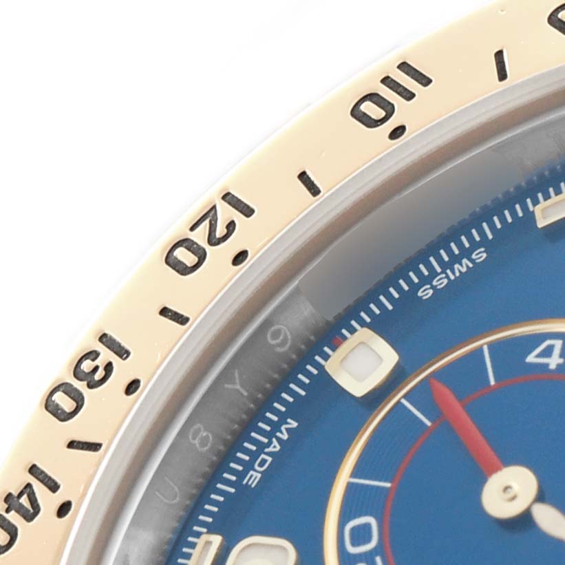 The image shows a close-up of a Rolex Daytona 116523 Men's Steel and Gold (two tone) Blue Dial watch, highlighting the bezel and part of the dial.