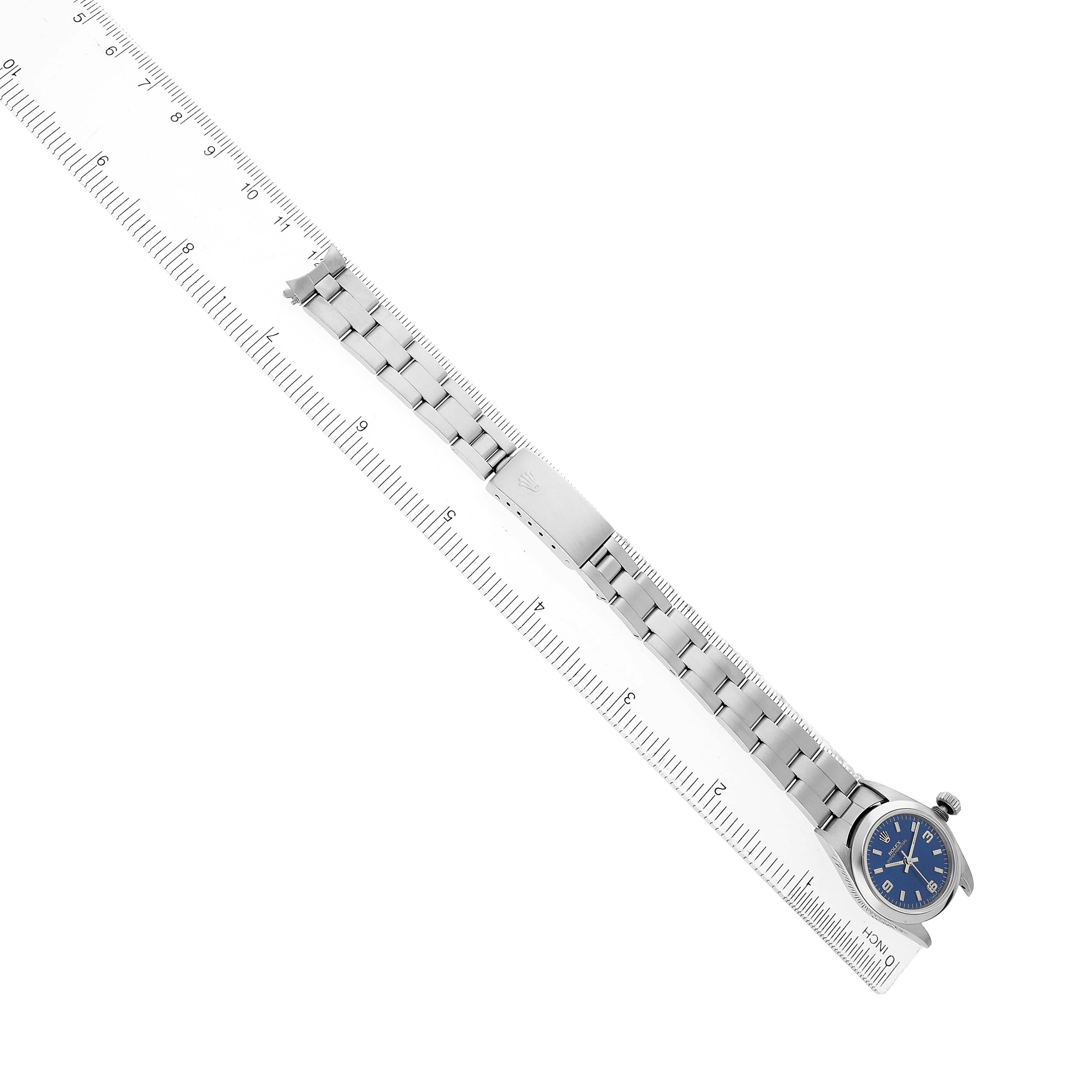 The Rolex Oyster Perpetual 67180 Women's Stainless Steel Blue Dial watch is shown from above, featuring the bracelet and clasp next to a ruler for scale.