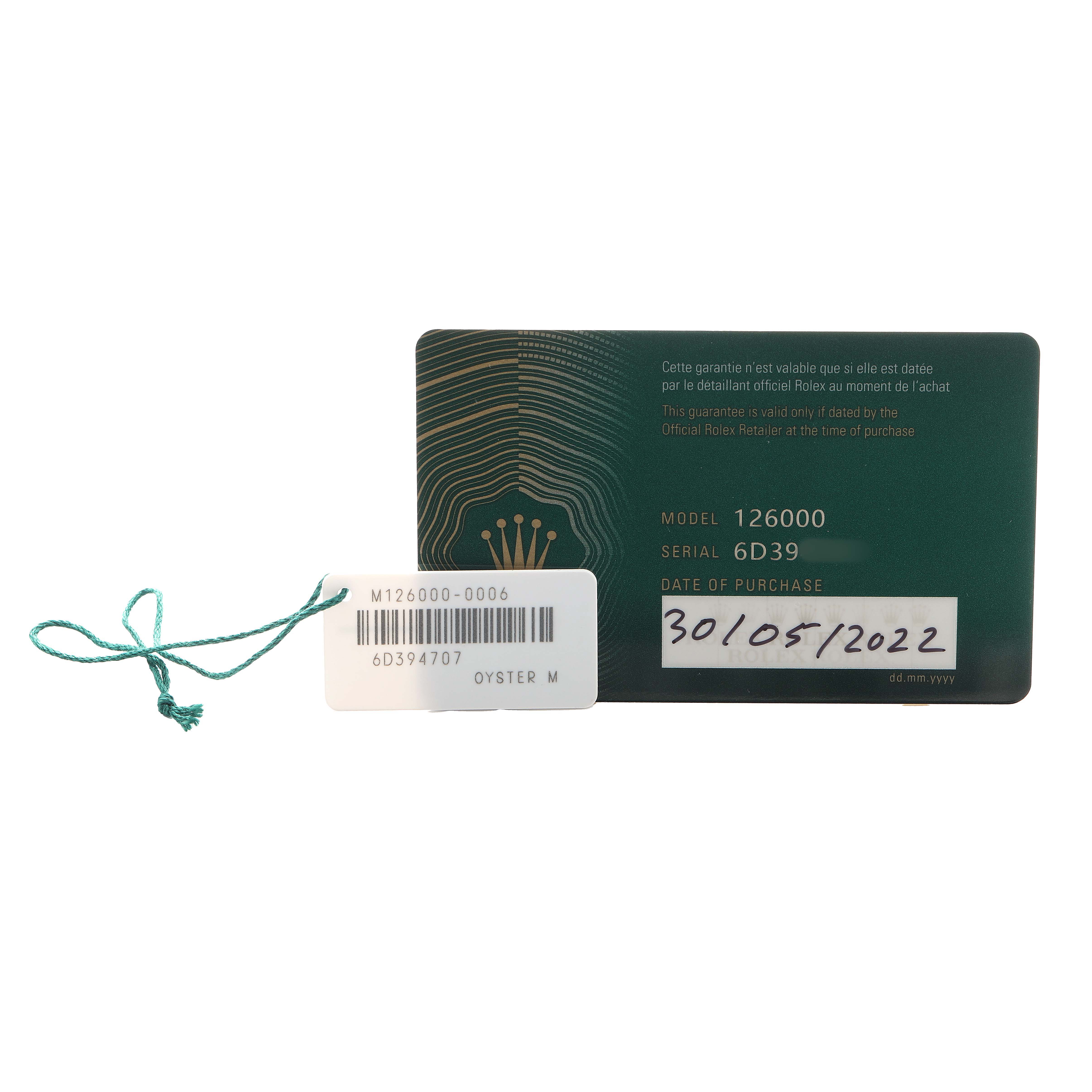 The image shows a Rolex Oyster Perpetual 126000 Men's Stainless Steel Blue Dial warranty card and a tag with model and serial numbers.