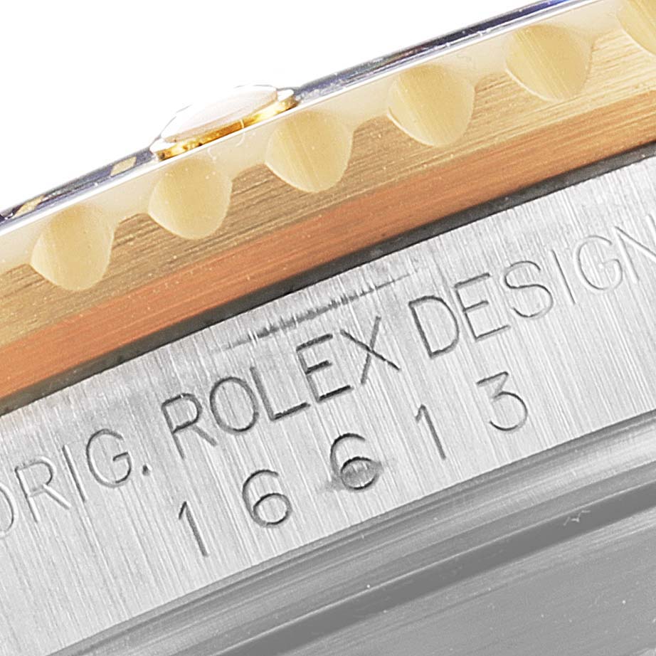 Close-up of the bezel and case of a Rolex Submariner 16613 Men
s Steel and Gold (two tone) Blue Dial 16613 Men
s Steel and Gold (two tone) Blue Dial, showing the model number 16613 and "ROLEX DESIGN" engraving.