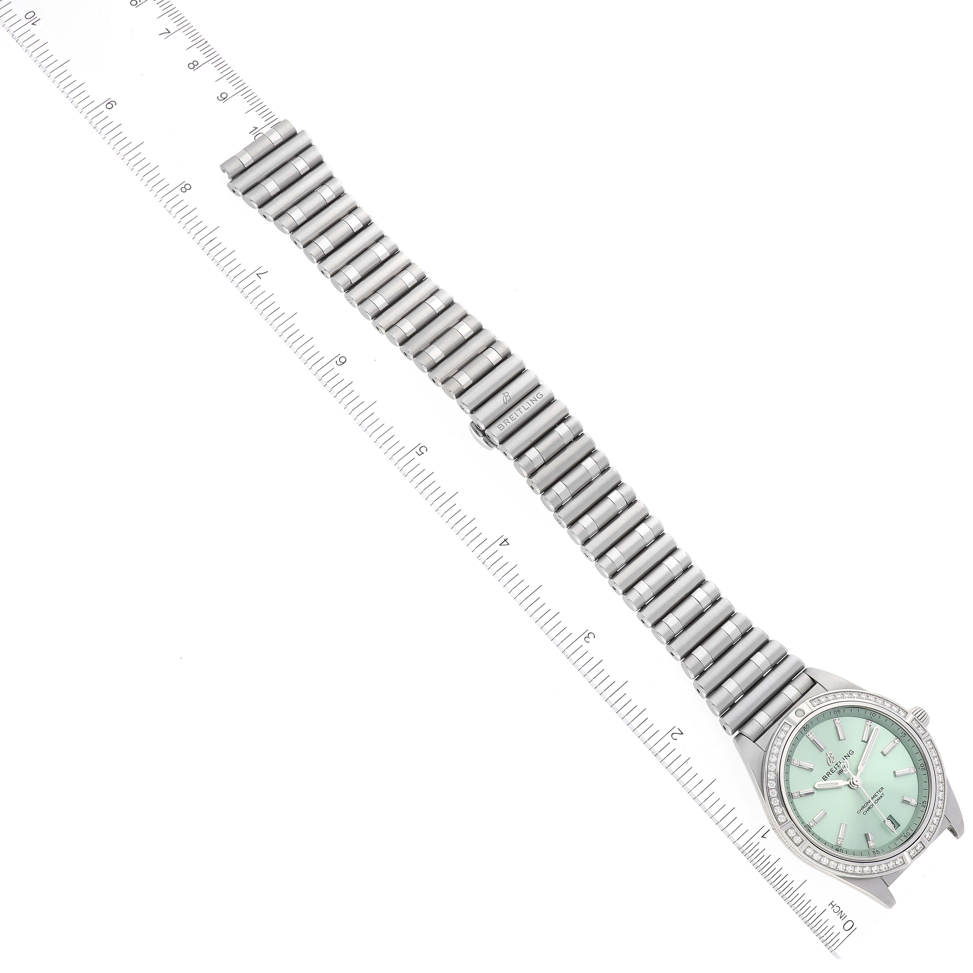 The Breitling A10380591L1A1 Women's Stainless Steel Green Dial A10380591L1A1 Women's Stainless Steel Green Dial Chronomat Green Dial Steel Diamond Ladies Watch A10380 is shown from a top-down angle, displaying its face and bracelet alongside a ruler for scale.