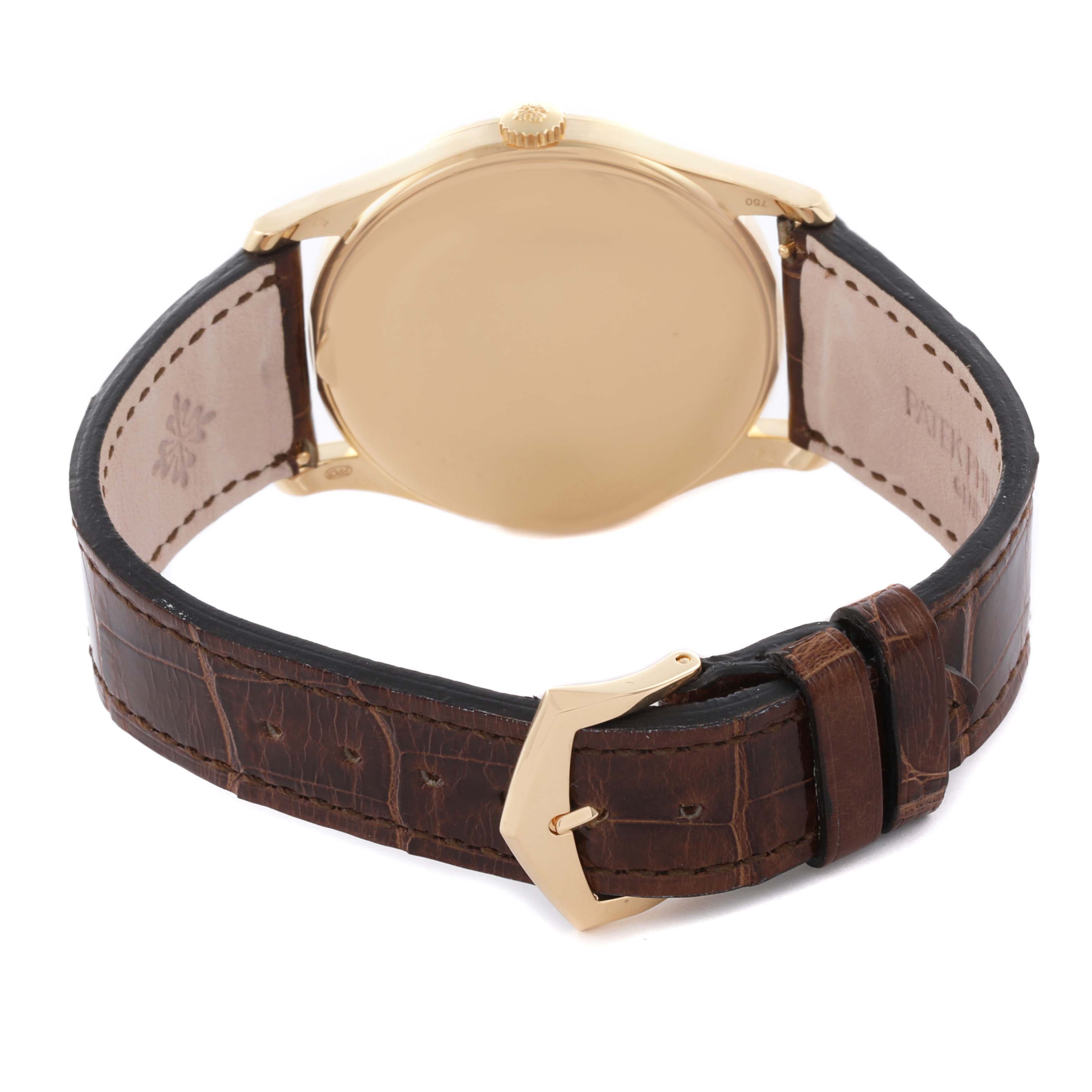 The image shows the back of a Patek Philippe Calatrava 5196J Men's Yellow Gold Silver Dial 5196J Men's Yellow Gold Silver Dial watch, focusing on the case, crown, and leather strap.