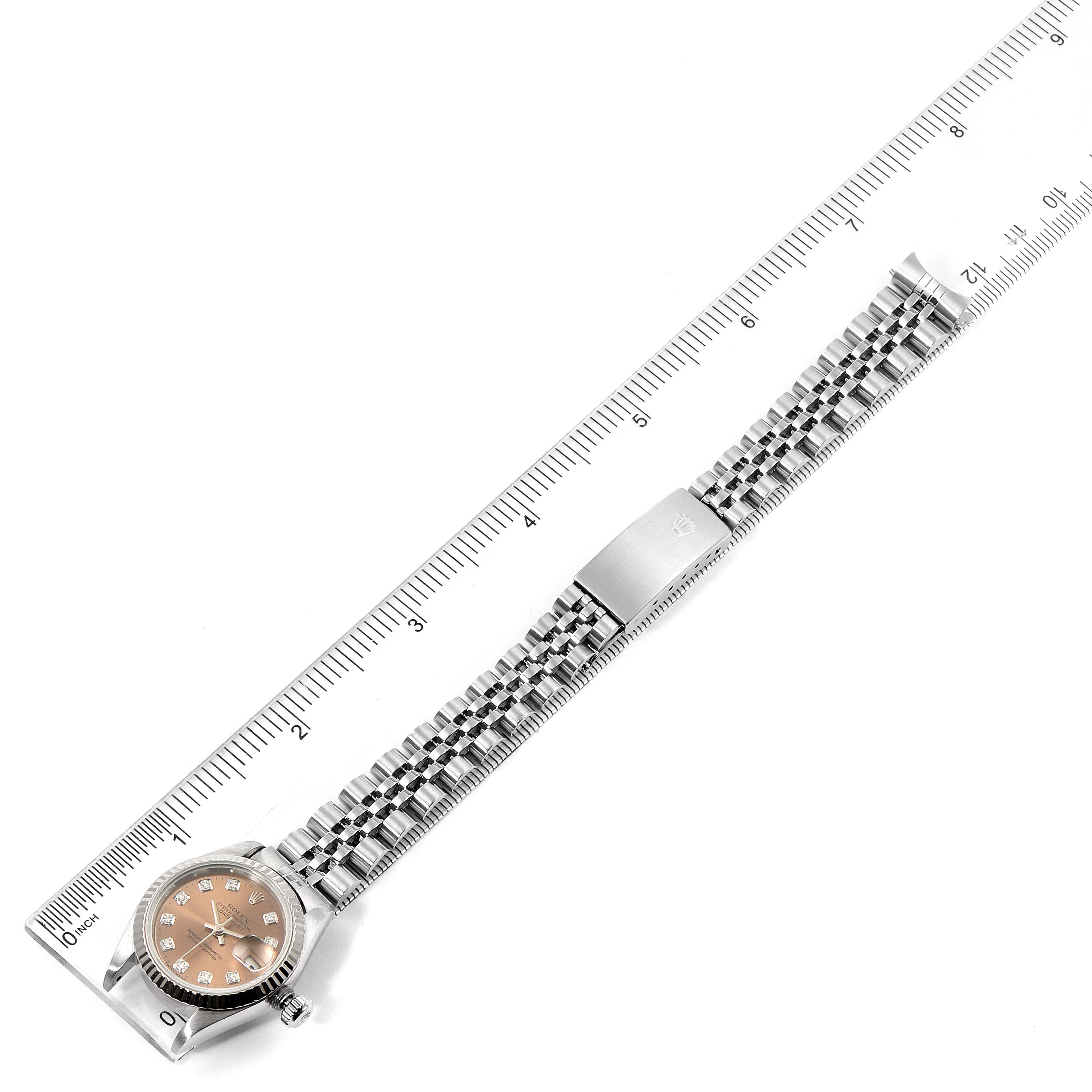 This image shows a top-down view of a Rolex Datejust 69174 Women's Stainless Steel Pink Dial 69174 Women's Stainless Steel Pink Dial watch with its bracelet laid flat alongside a ruler.