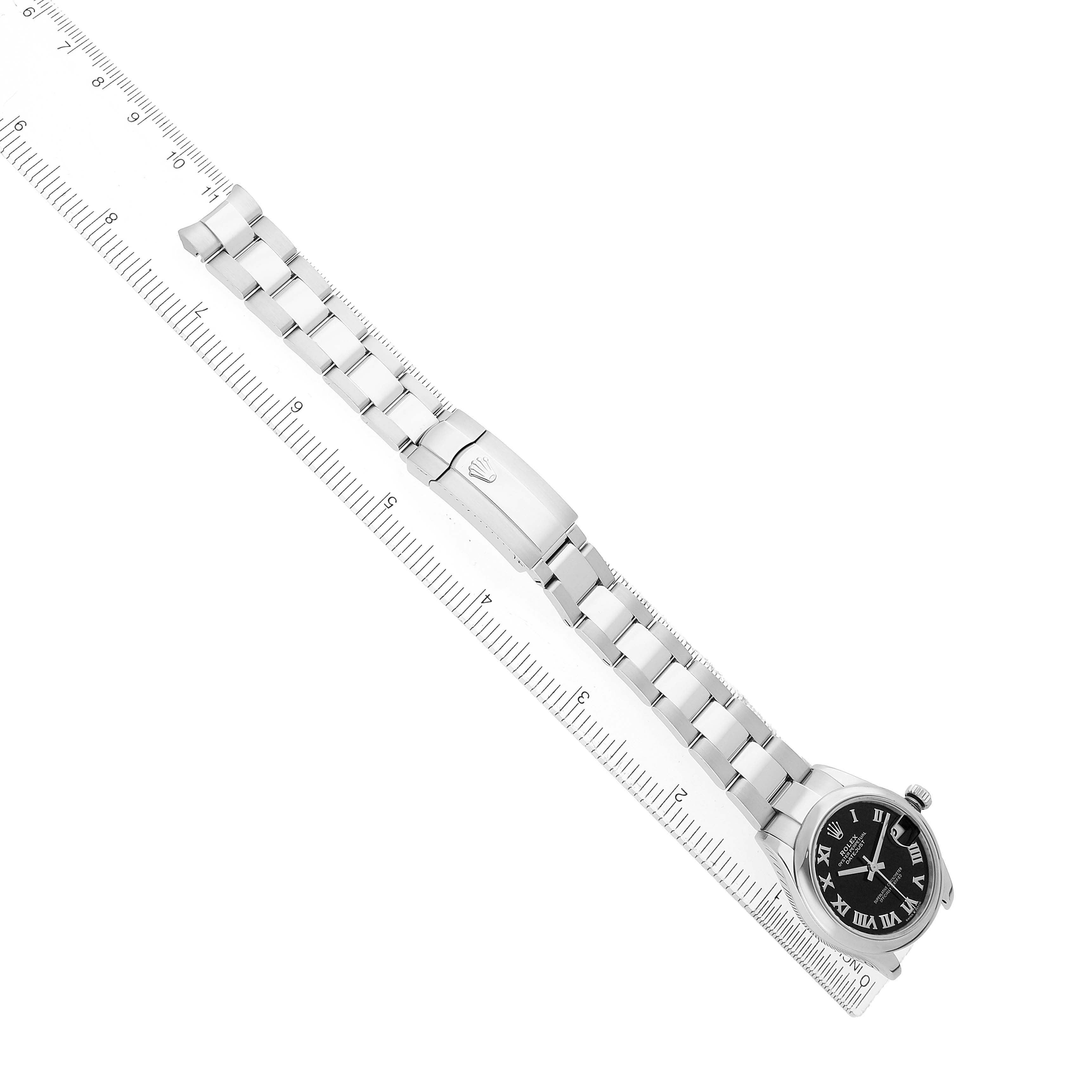 The image shows a Rolex Mid-Size 278240 Women's Stainless Steel Black Dial watch from a top view, highlighting the bracelet, clasp, and face beside a ruler.