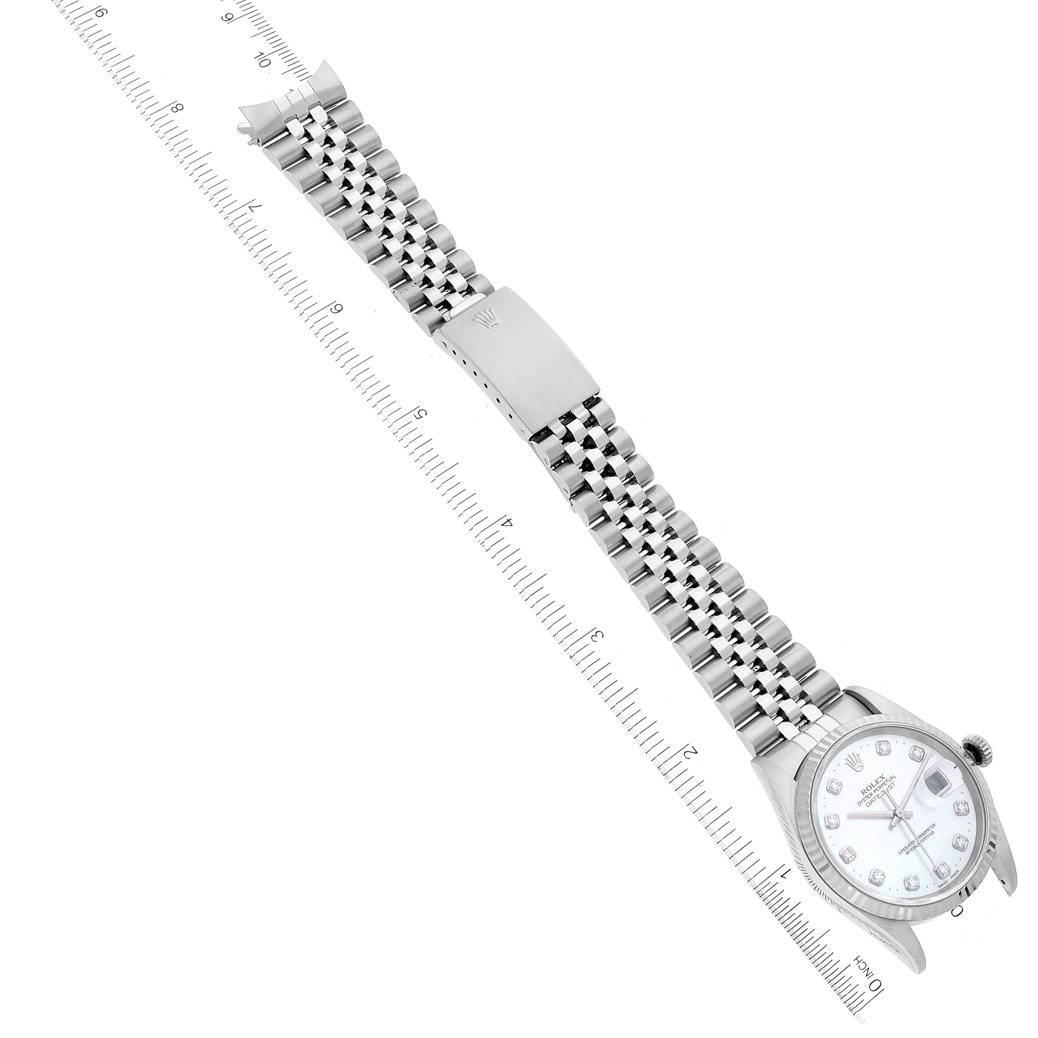 The image shows a top-down view of a Rolex Datejust 16234 Men's Stainless Steel Mother of Pearl Dial 16234 Men's Stainless Steel Mother of Pearl Dial watch featuring its dial, bezel, crown, and Jubilee bracelet with a ruler beside it.