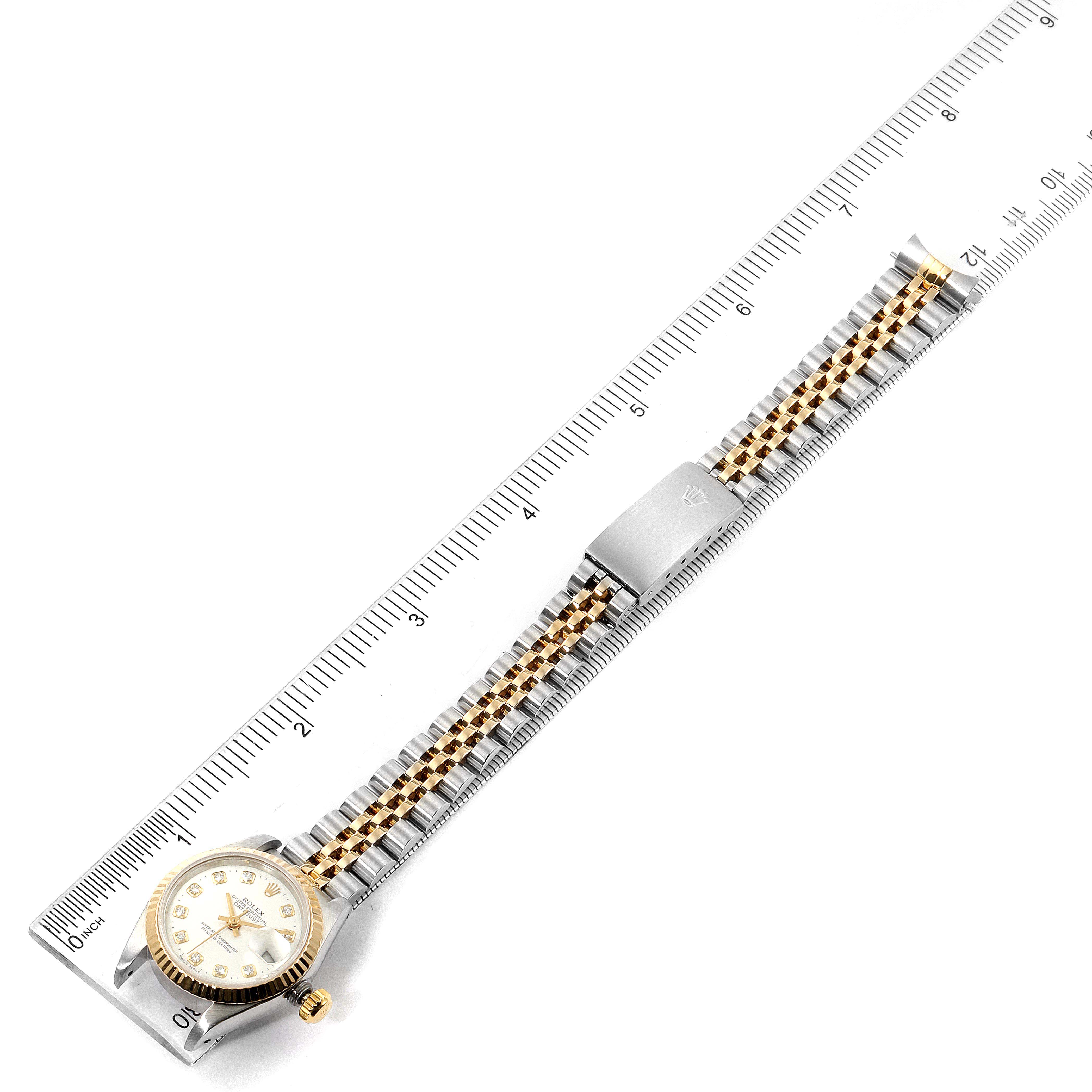 This is an overhead view of a Rolex Datejust 69173 Women's Steel and Gold (two tone) White Dial 69173 Women's Steel and Gold (two tone) White Dial watch showing the face, bezel, crown, bracelet, and clasp alongside a ruler.