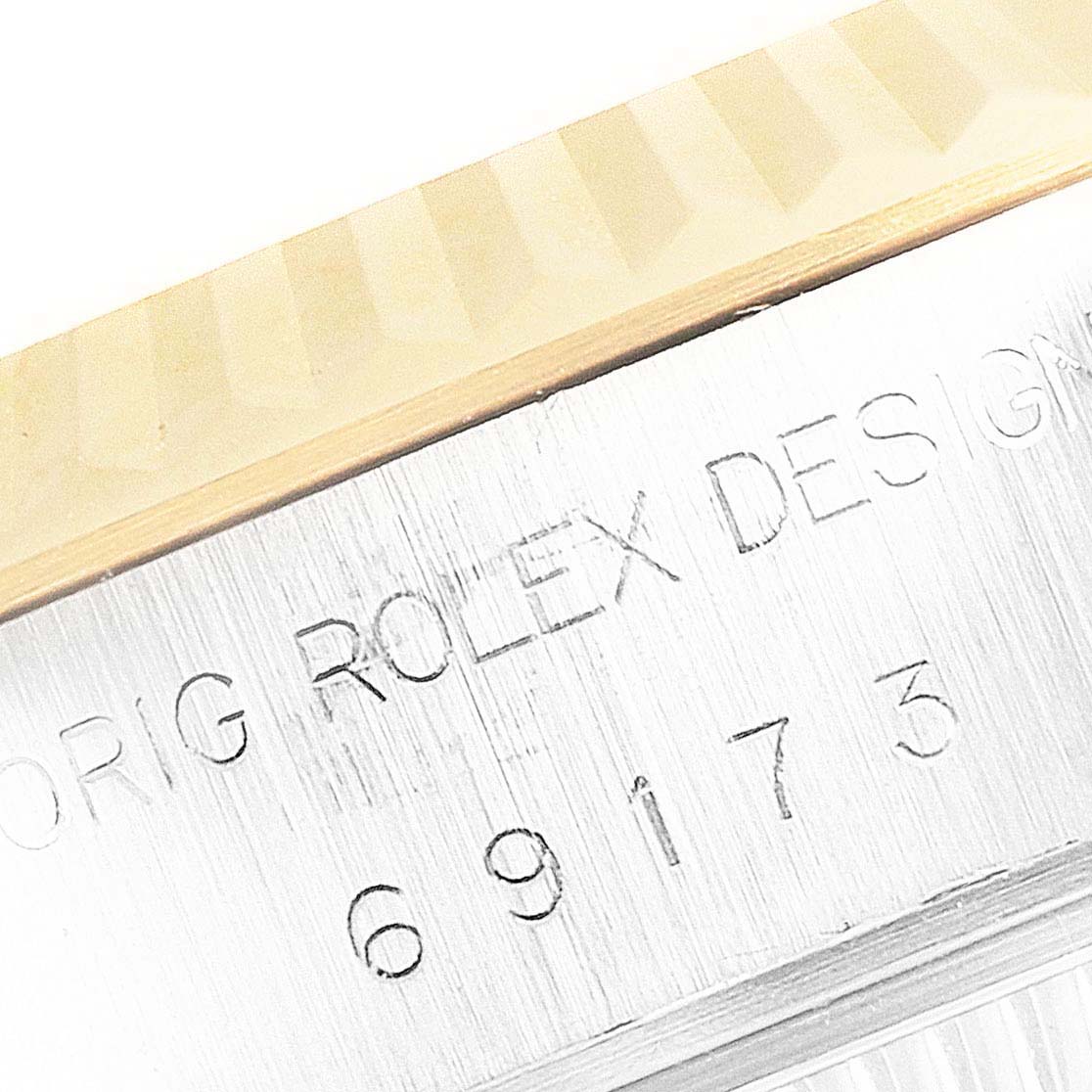 The image shows a close-up of the serial number and part of the fluted bezel of the Rolex Datejust 69173 Women's Steel and Gold (two tone) White Dial 69173 Women's Steel and Gold (two tone) White Dial watch.