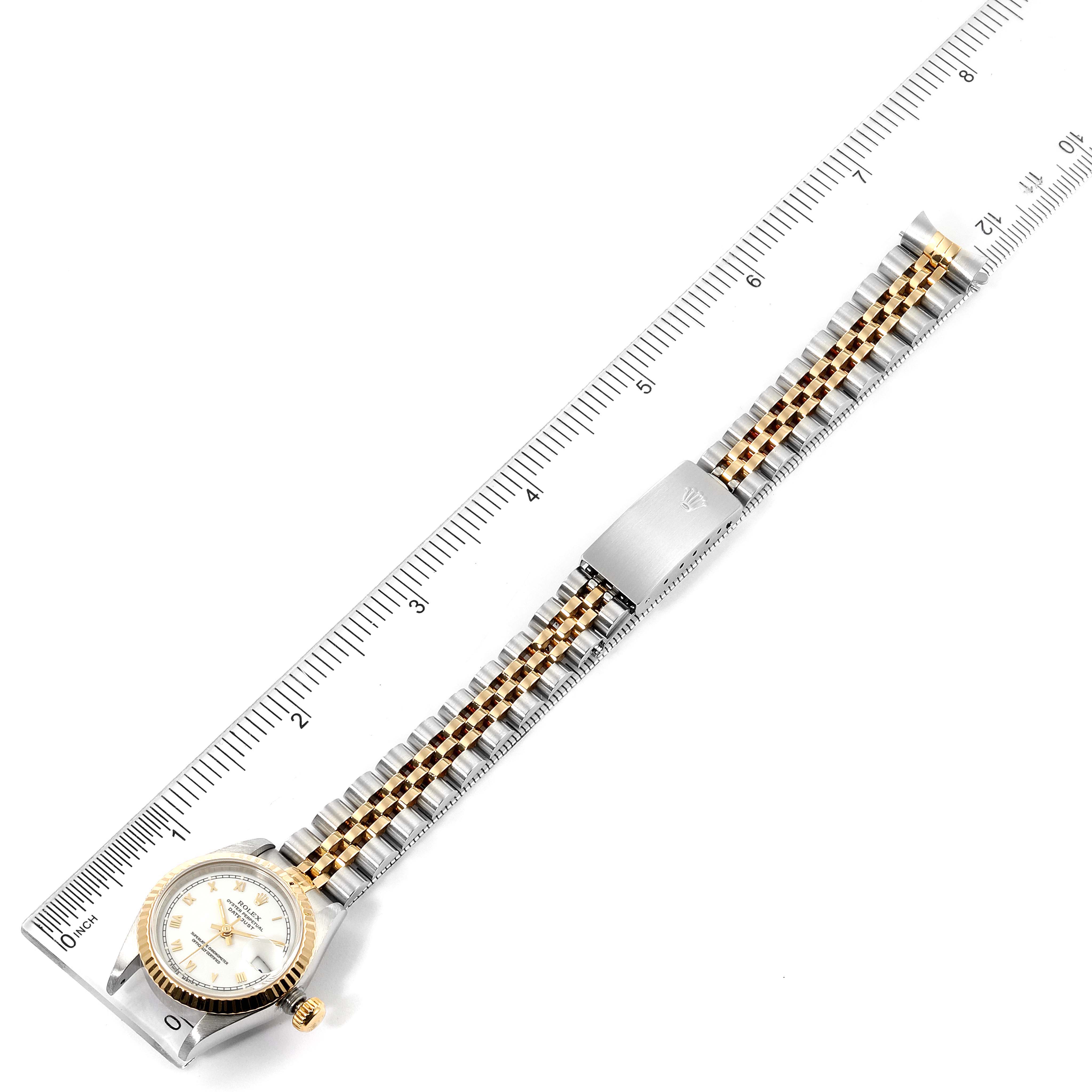 The Rolex Datejust 69173 Women's Steel and Gold (two tone) White Dial 69173 Women's Steel and Gold (two tone) White Dial watch is shown from a top view, including the face, band, and clasp, placed alongside a ruler for scale.