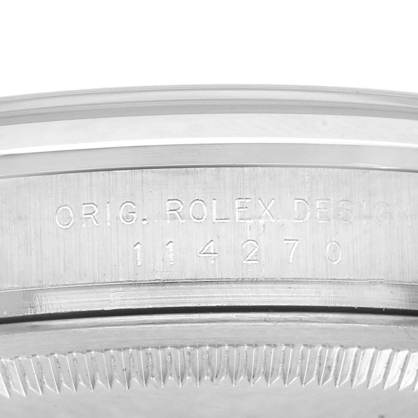 The image shows the side view of a Rolex Explorer 114270 Men
s Stainless Steel Black Dial 114270 Men
s Stainless Steel Black Dial watch case with engravings and part of the bezel.