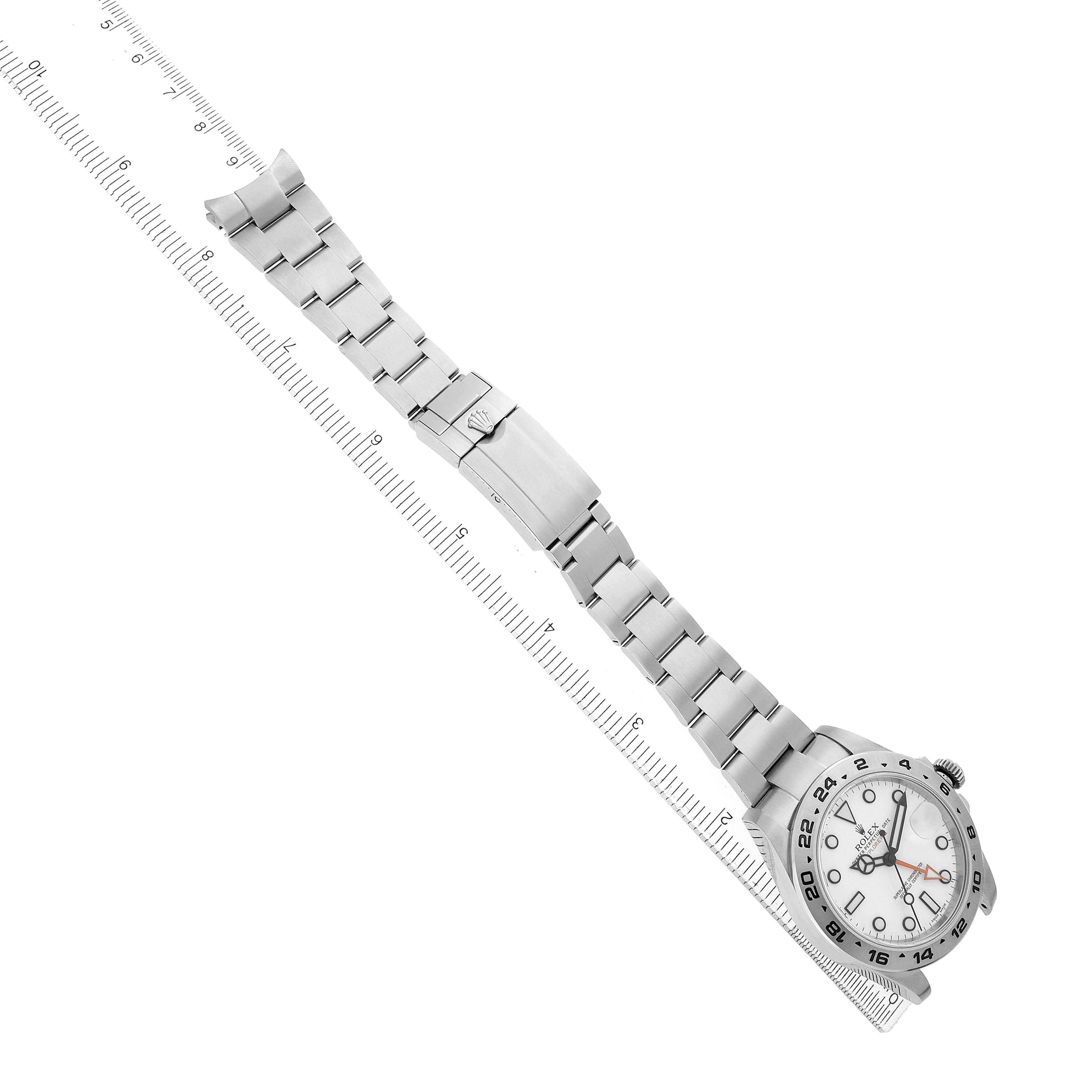 The Rolex Explorer 216570 Men's Stainless Steel White Dial watch is shown from the top angle, displaying the full bracelet and clasp alongside a ruler for scale.