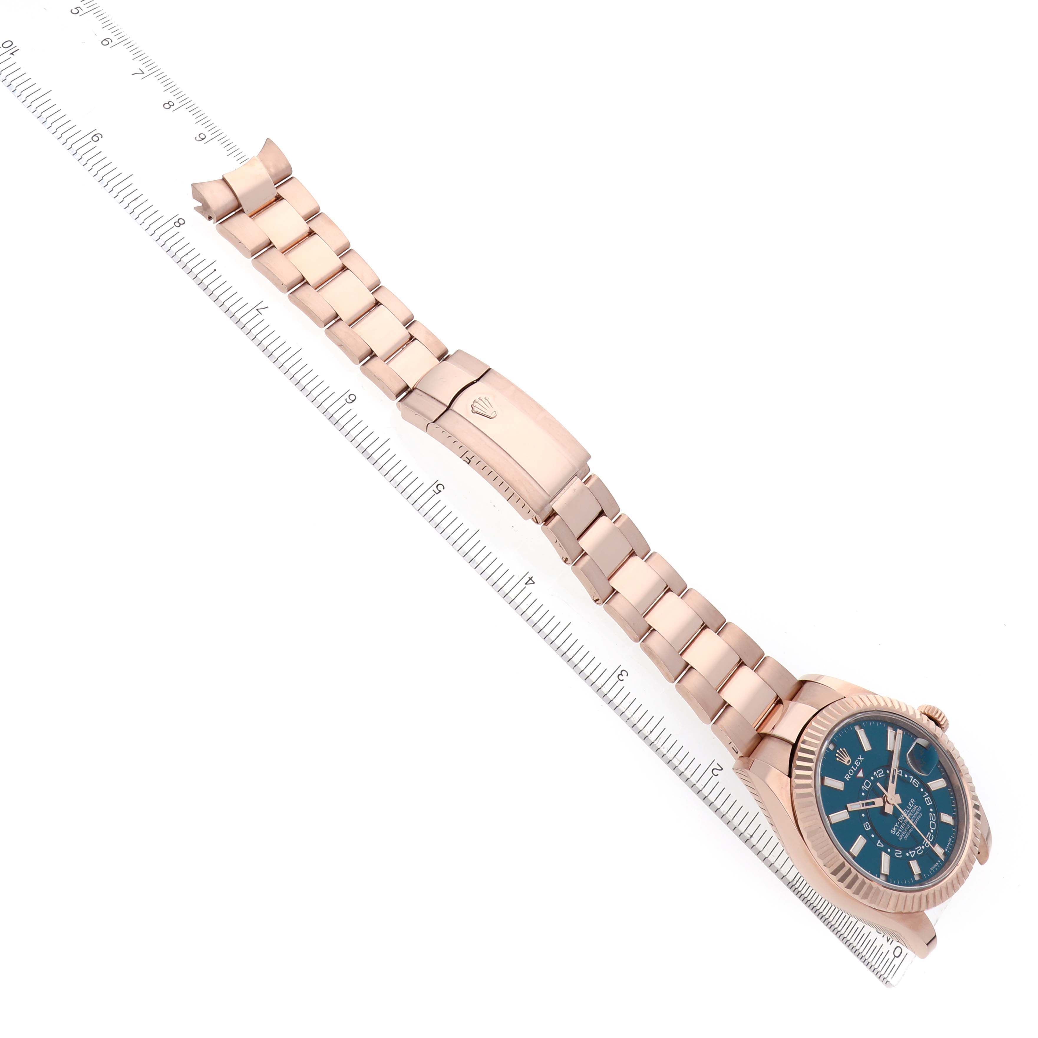 The Rolex Sky-Dweller 336935 Men's Rose Gold Blue Dial watch is shown from above, displaying the face, bezel, and full bracelet laid out near a ruler.
