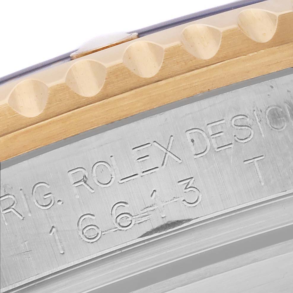 The image shows a close-up of the Rolex Submariner 16613 Men's Steel and Gold (two tone) Blue Dial 16613 Men's Steel and Gold (two tone) Blue Dial's bezel and engraved side of the case.