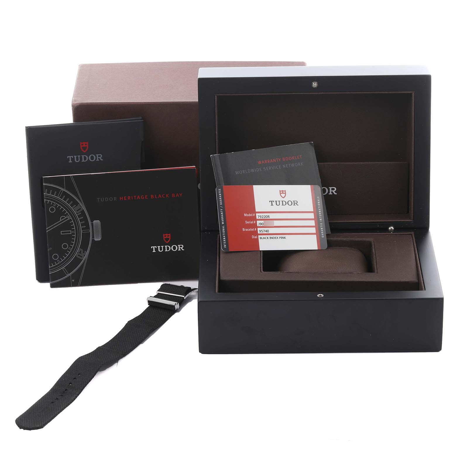 The image shows the Tudor Heritage Black Bay 79220R Men
s Stainless Steel Black Dial 79220R Men
s Stainless Steel Black Dial packaging with manuals, a warranty card, and a strap, all from a frontal angle.