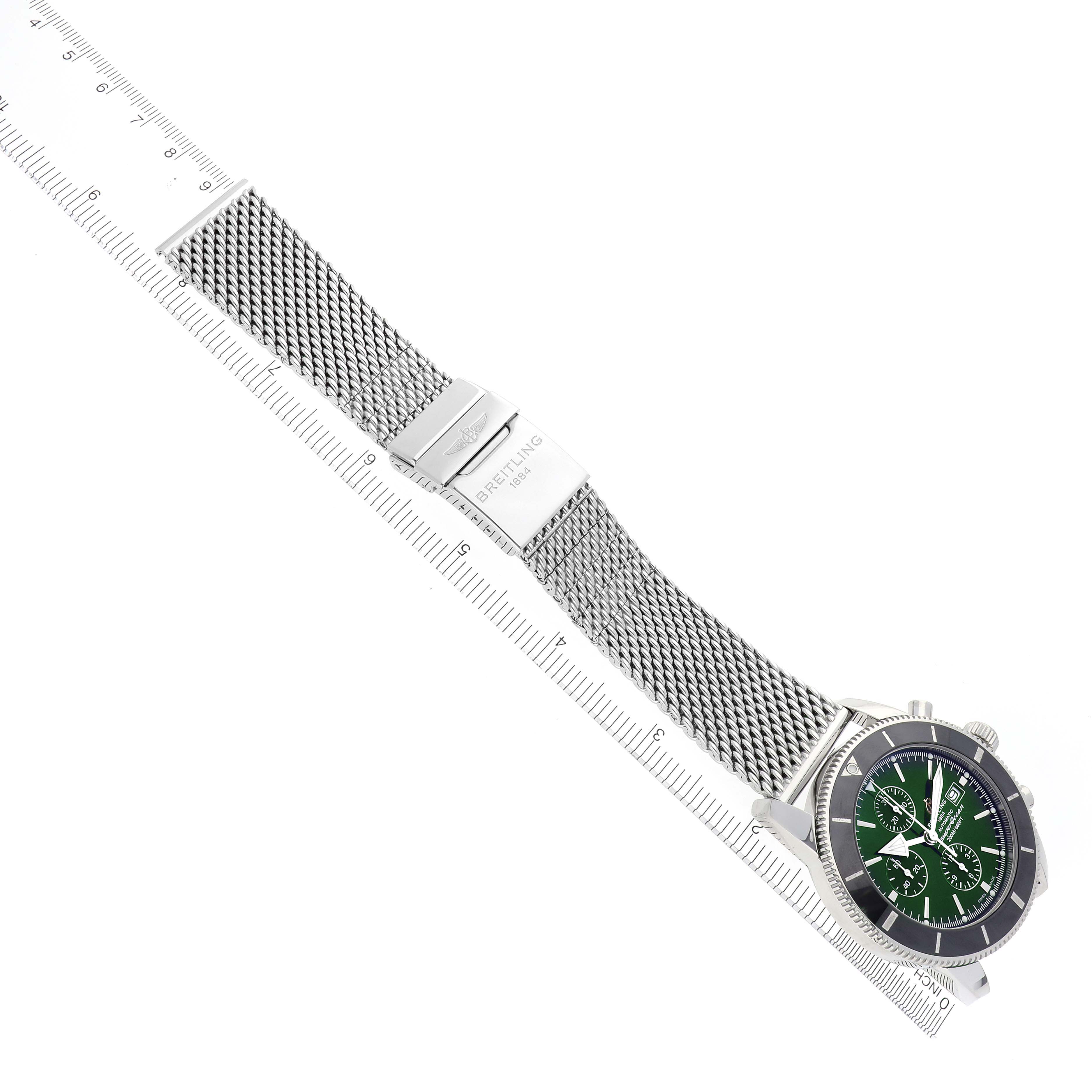 The Breitling Superocean A13312 Men's Stainless Steel Green Dial A13312 Men's Stainless Steel Green Dial watch is shown in a top-down view, displaying the mesh bracelet, clasp, and green dial with a ruler alongside.