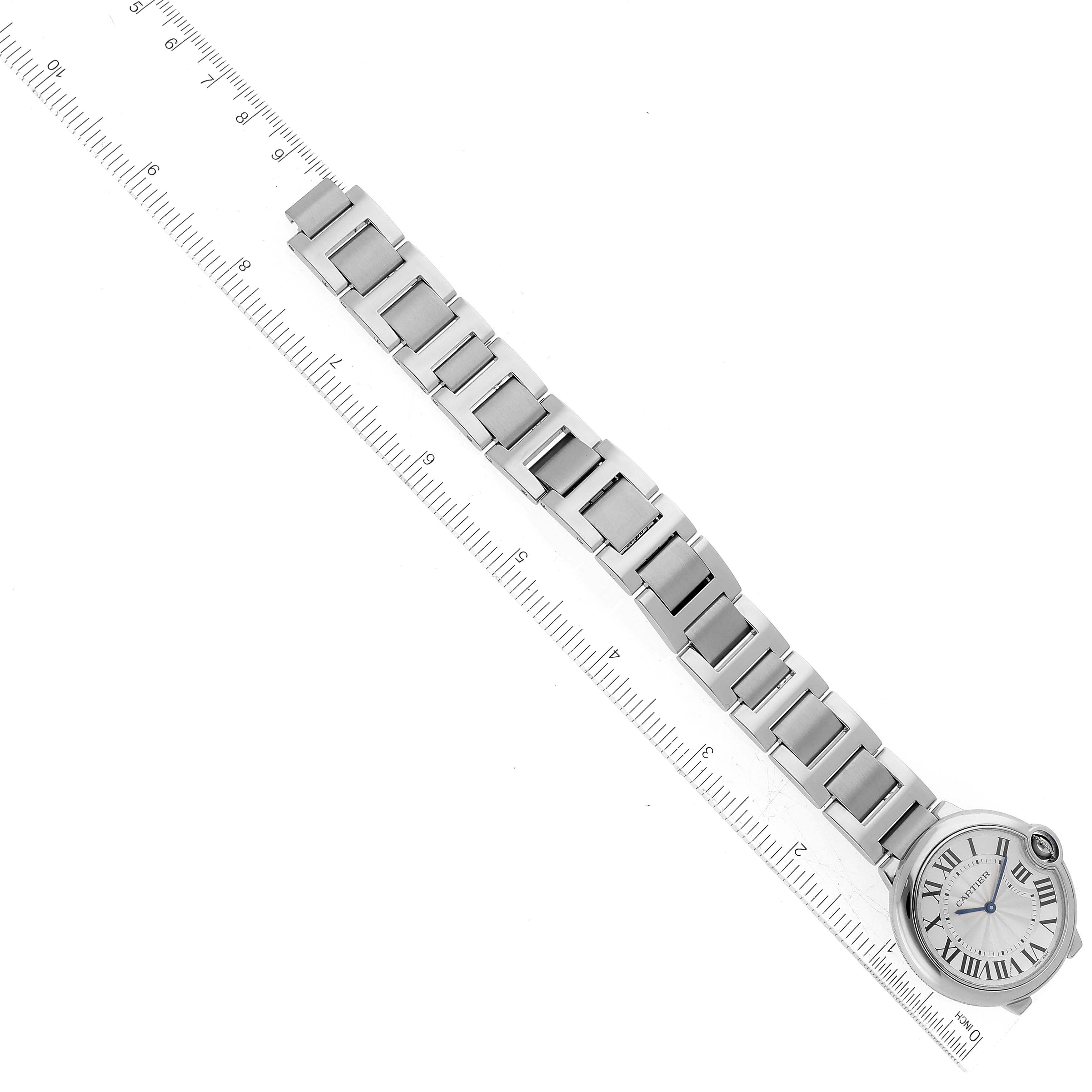The image shows a top-down view of a Cartier Ballon Bleu W69011Z4 Men
s Stainless Steel Silver Dial W69011Z4 Men
s Stainless Steel Silver Dial watch with a stainless steel bracelet and a ruler for scale.