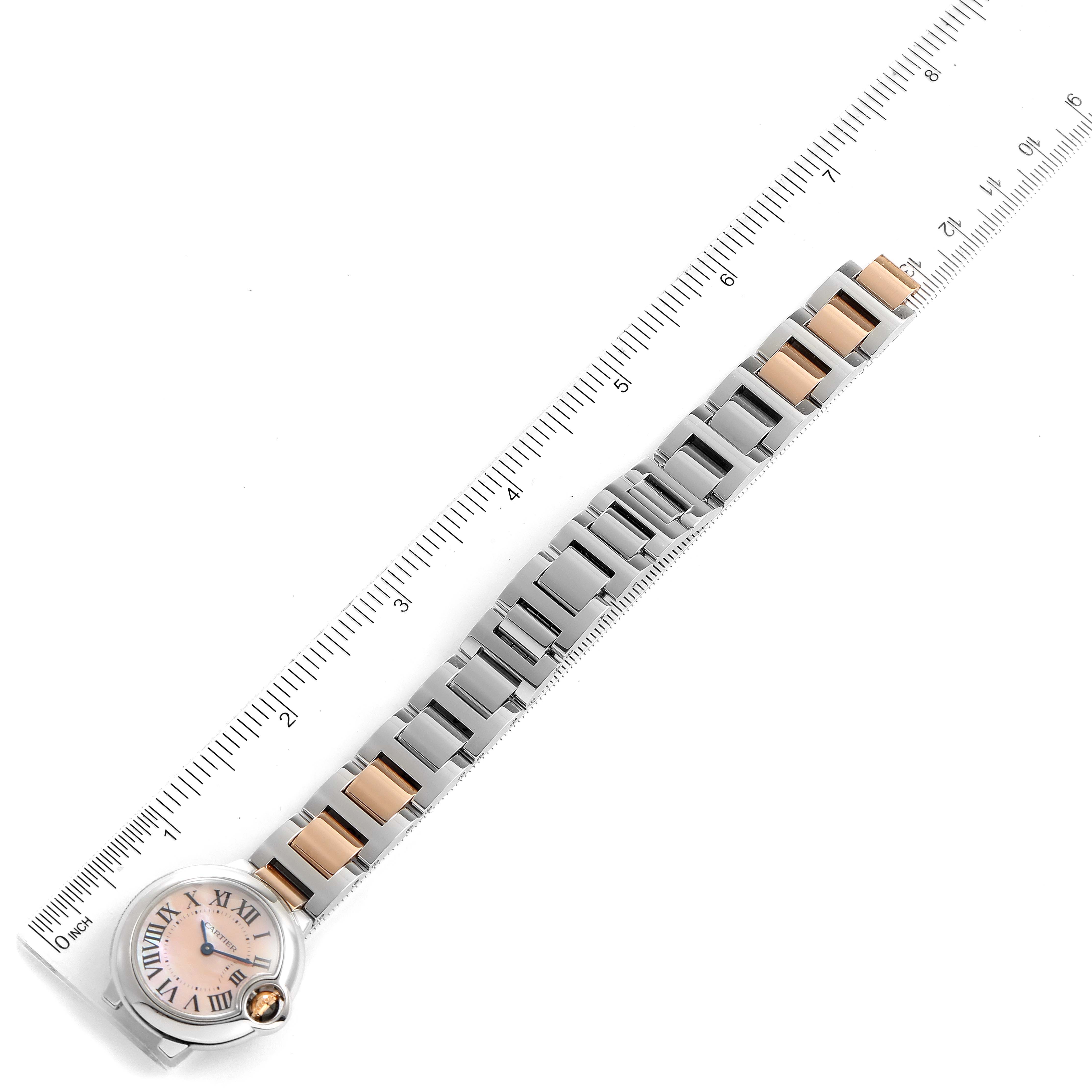 This image shows the Cartier Ballon Bleu W6920034 Women
s Steel and Gold (two tone) Mother of Pearl Dial W6920034 Women
s Steel and Gold (two tone) Mother of Pearl Dial watch placed alongside a ruler, highlighting its full face and metal band.