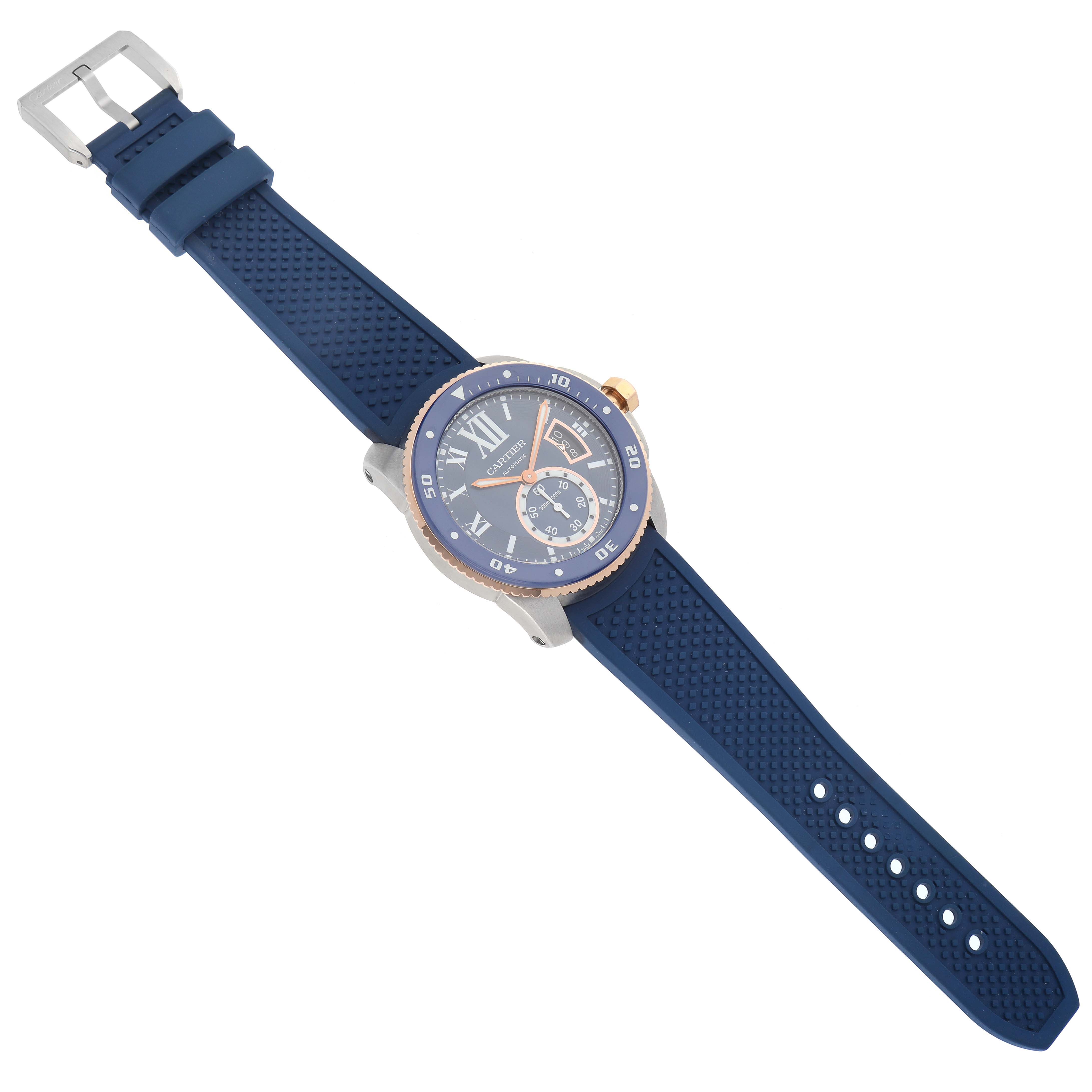 The Calibre de Cartier watch is shown from a top-down angle, displaying its face, blue rubber strap, and bezel.