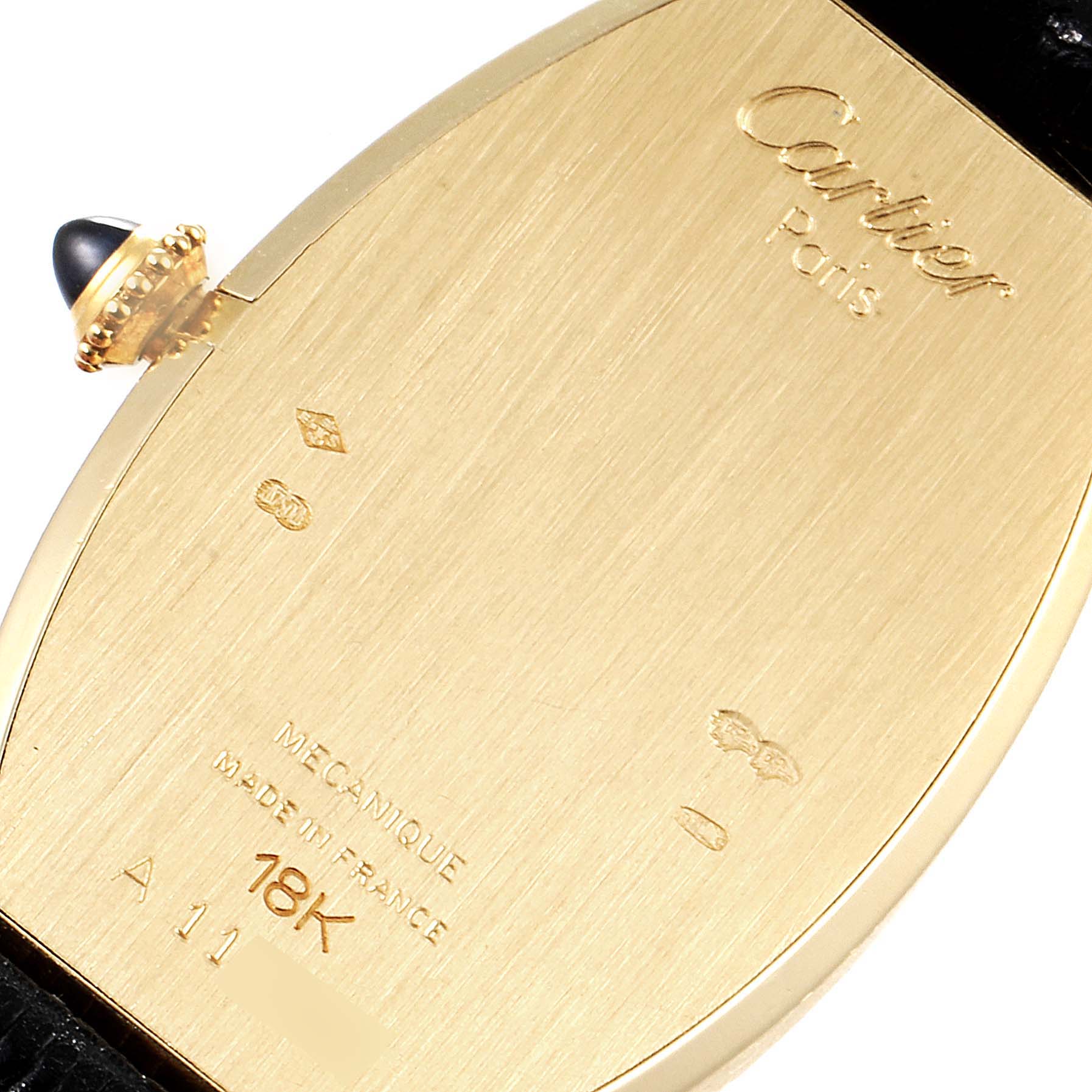 The image shows the back of a Cartier Tortue Women's Yellow Gold Silver Dial Women's Yellow Gold Silver Dial watch case, displaying engravings and the crown with a gemstone.